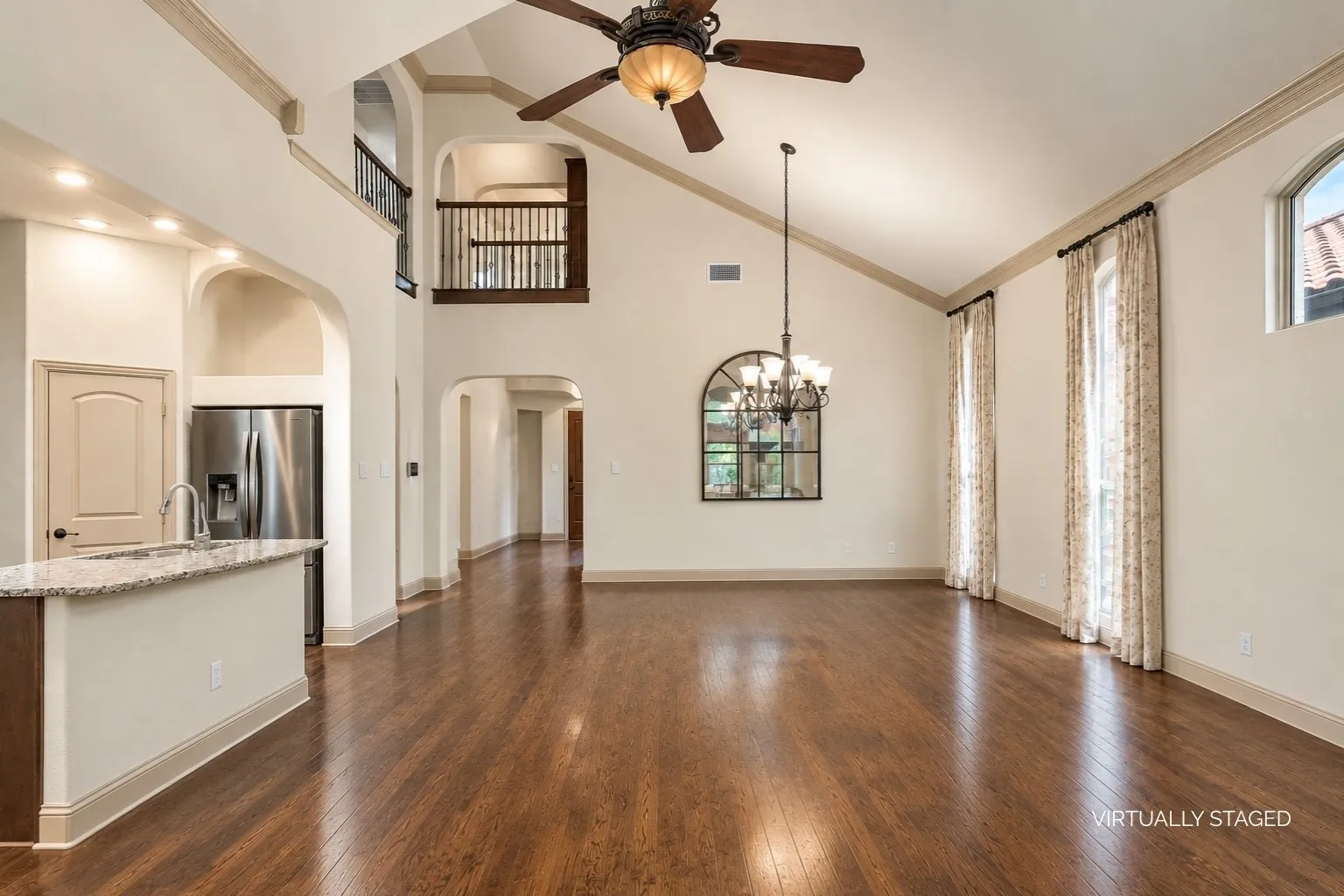 Open living room space with dramatic soaring ceilings, light fixtures and ceiling fan