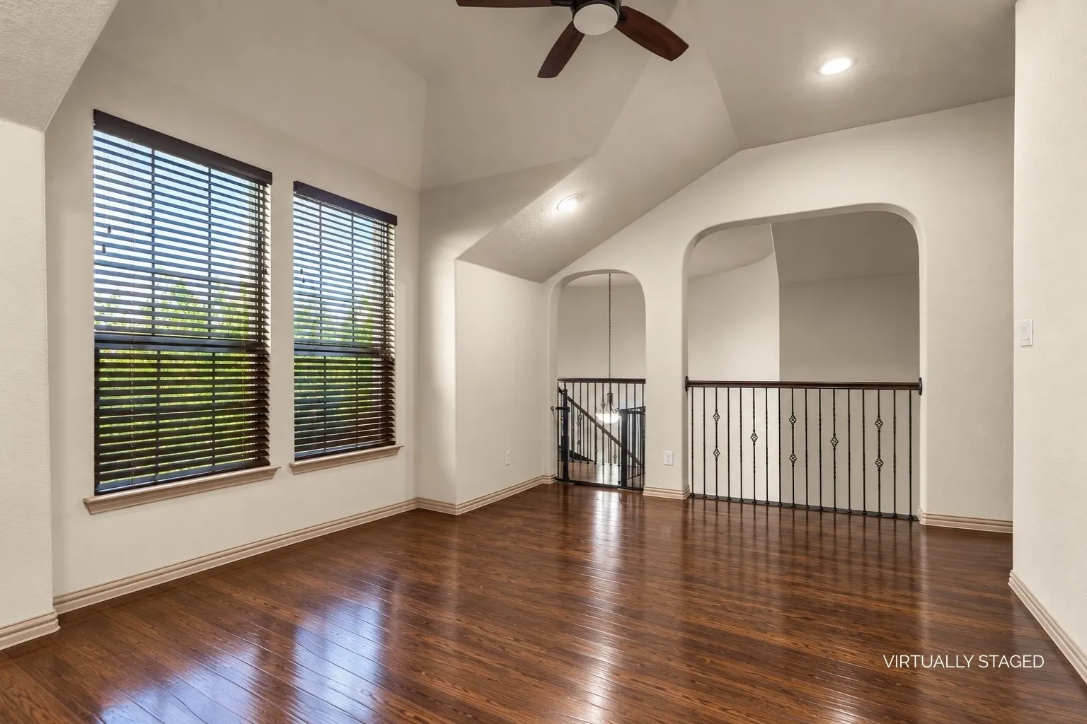 Upstairs flex living area with large windows and ceiling fan overlooking the spiral staircase