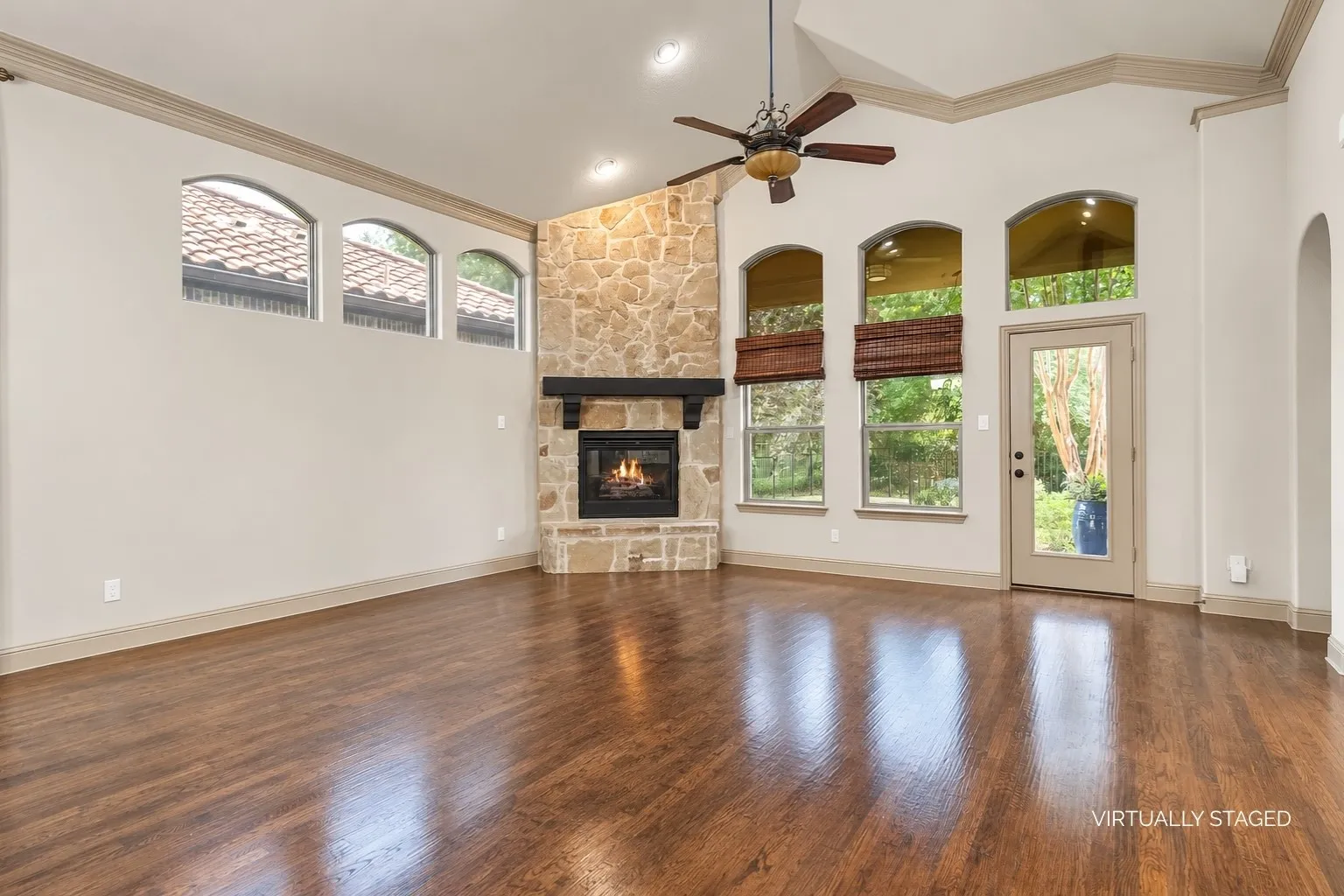 Living room with large arched windows showing the lush backyard