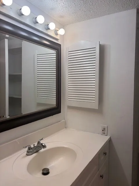 Bathroom with a textured ceiling and vanity