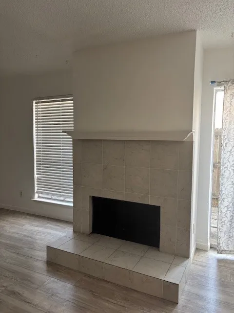 Detailed view of a tile fireplace, wood finished floors, and a textured ceiling