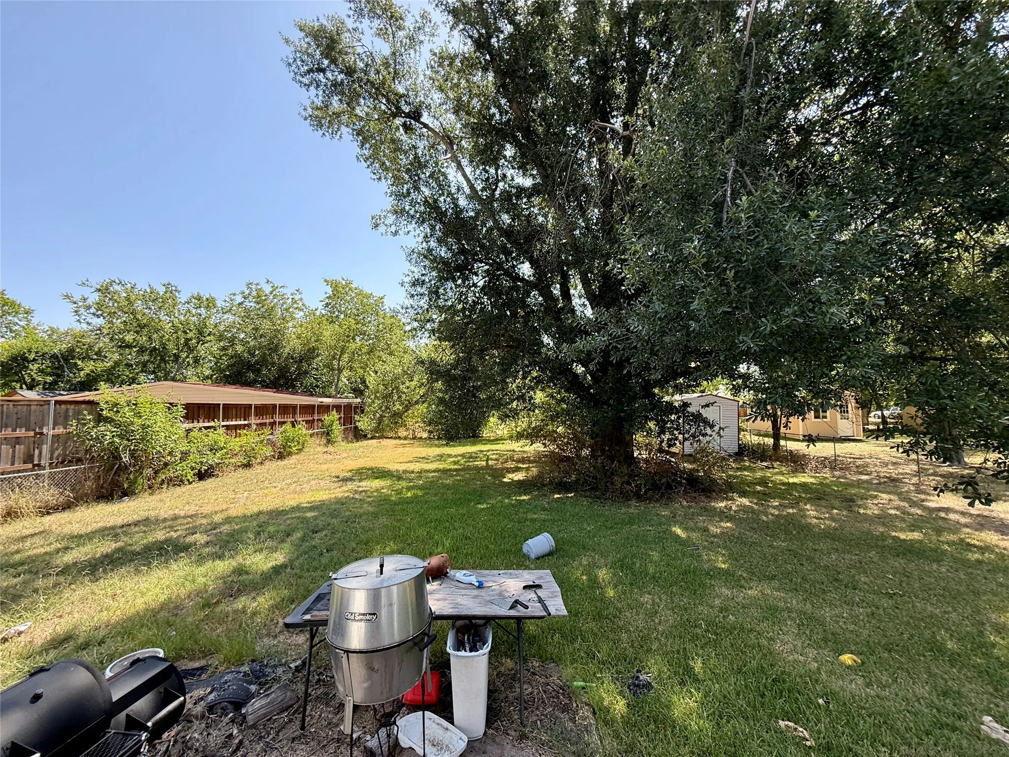 Expansive backyard with a substantial mature tree, offering abundant natural shade