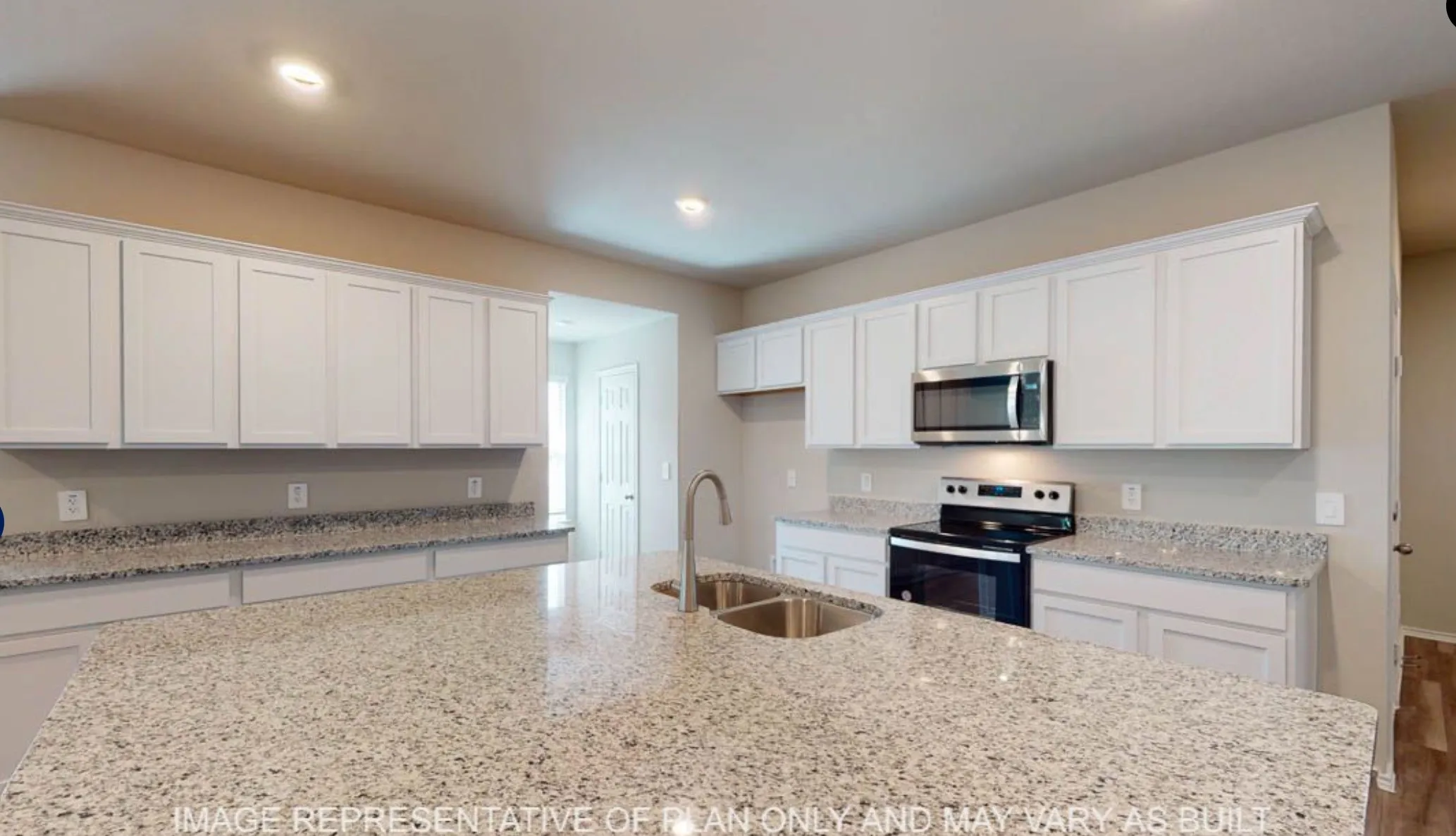 Large kitchen island with a double basin sink, white cabinetry, integrated microwave, and electric range