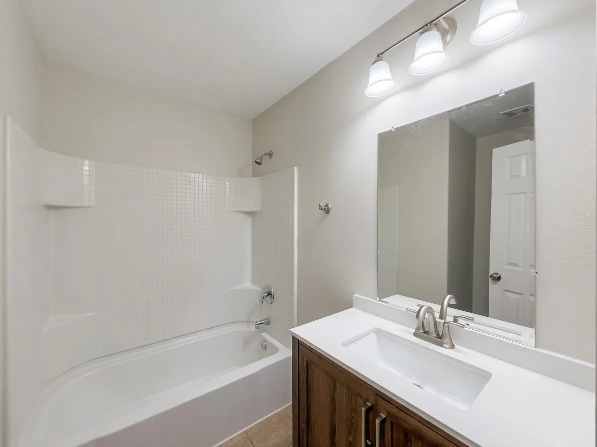 White tub and shower combination with a textured tile surround