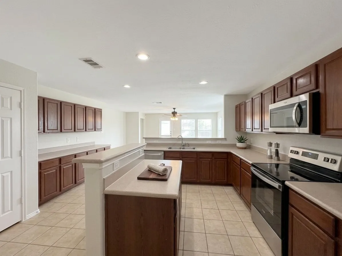 Kitchen featuring extensive cabinetry, tile flooring, stainless steel appliances, a double basin sink, and recessed lighting
