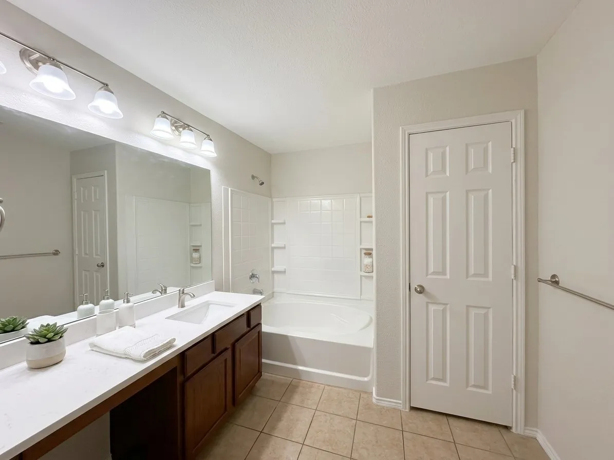 Dual vanity with a single sink, an integrated bathtub and shower, and tiled flooring