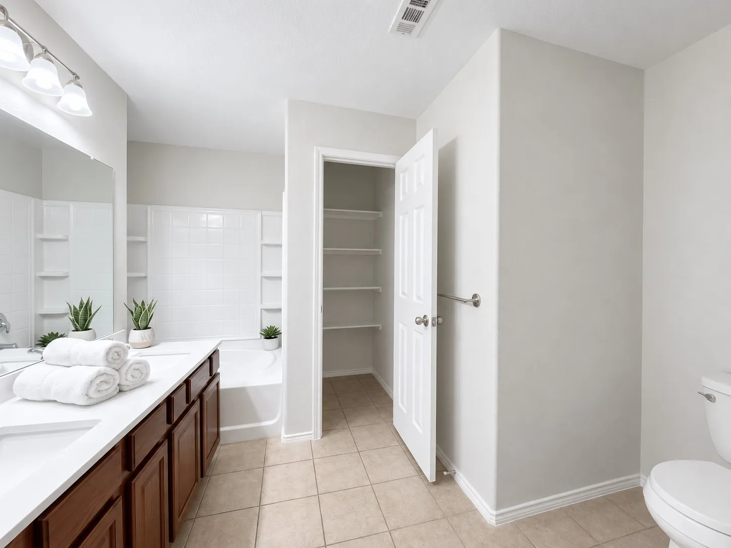 Bathroom featuring a dual vanity with dark wood-finish cabinetry, a white countertop, and a built-in bathtub with subway tile surround