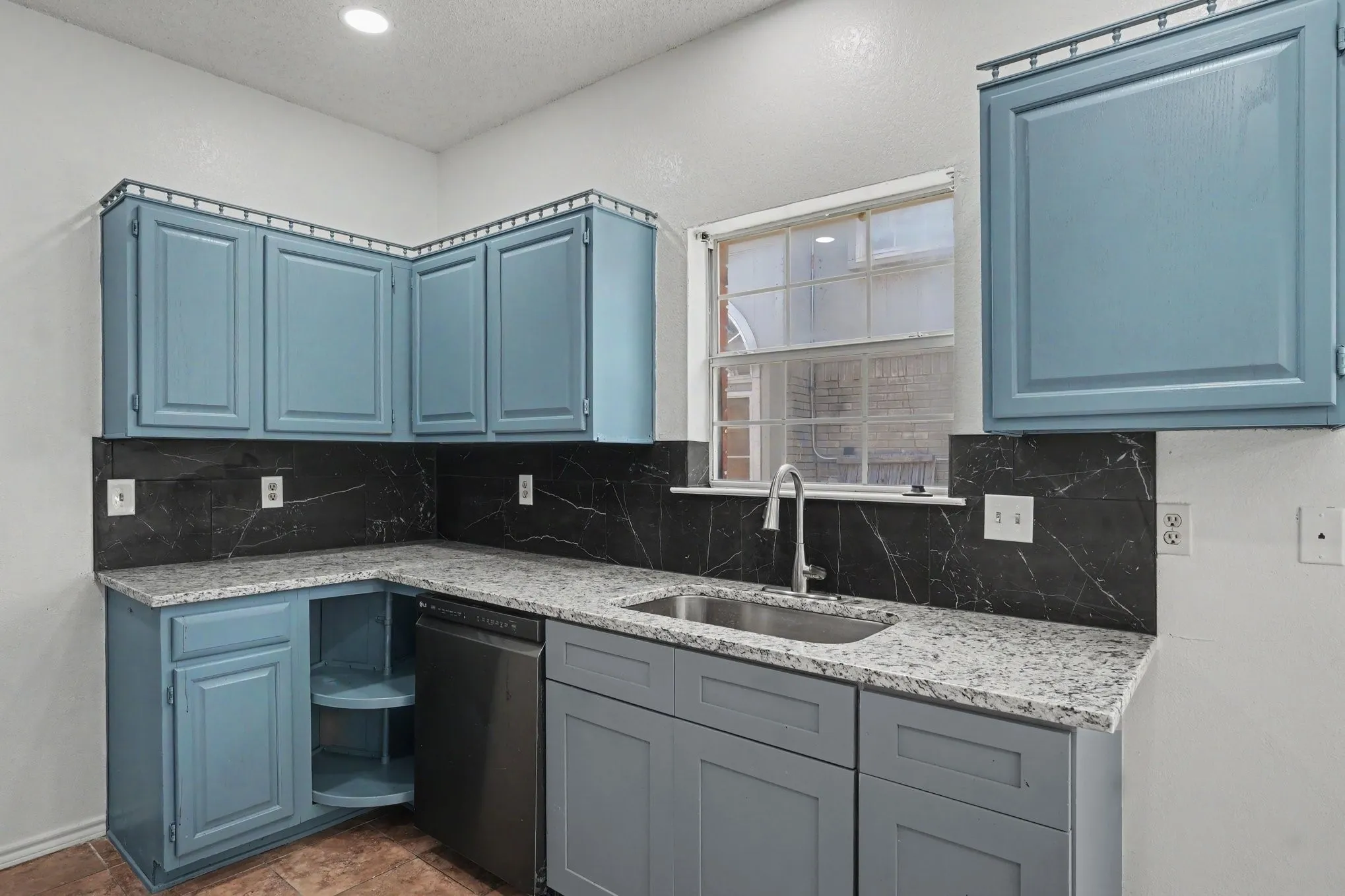 Granite-style countertops, stainless steel sink with a gooseneck faucet, black marble-look backsplash, recessed lighting, and painted cabinetry