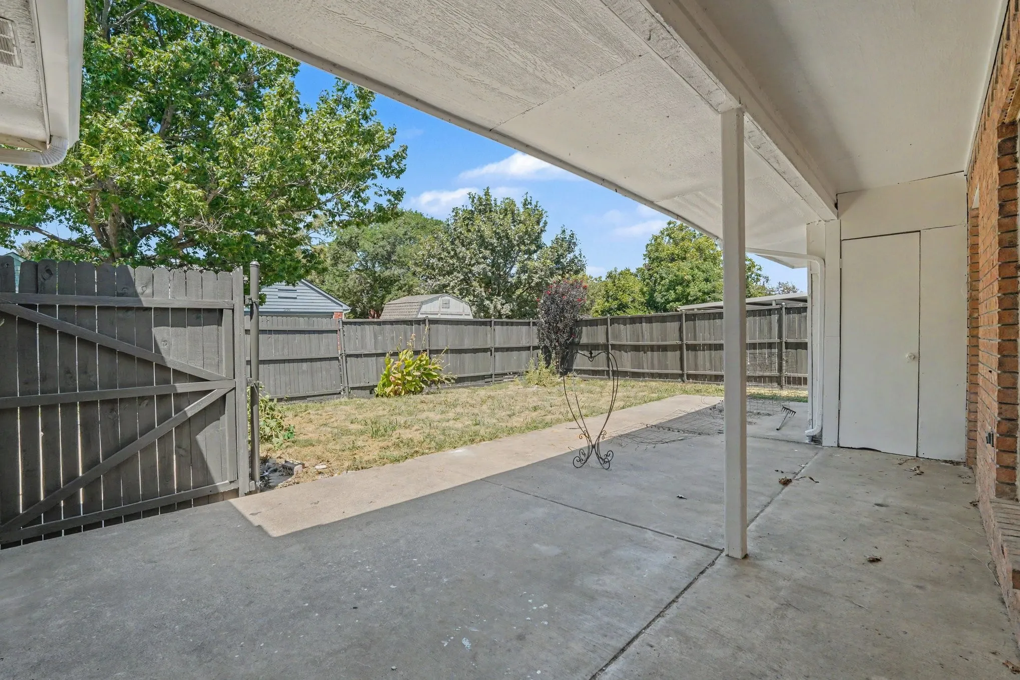 Covered concrete patio with a full privacy fence