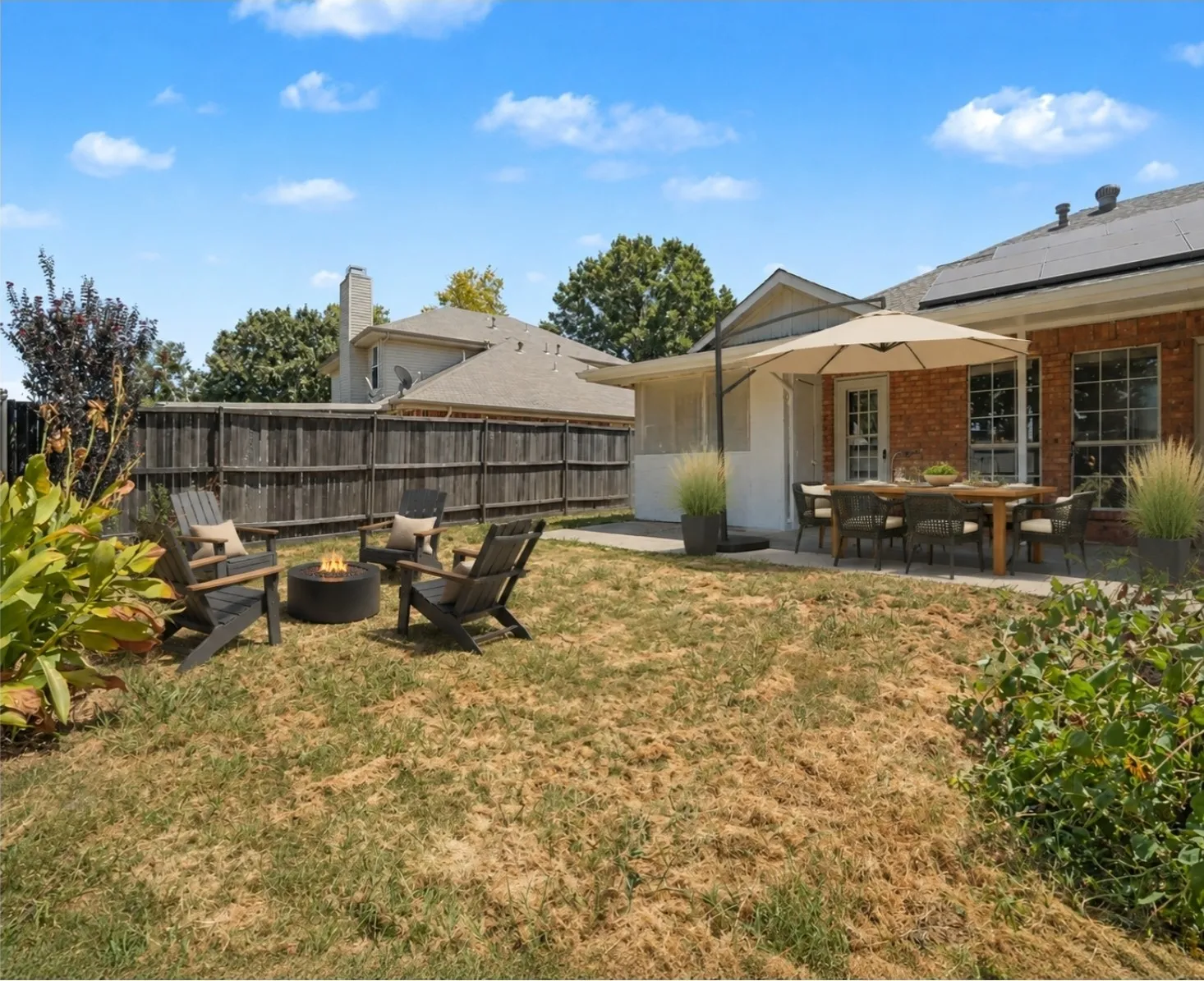 EI Staging. Expansive backyard featuring a privacy fence, brick exterior, concrete patio, and mature landscaping