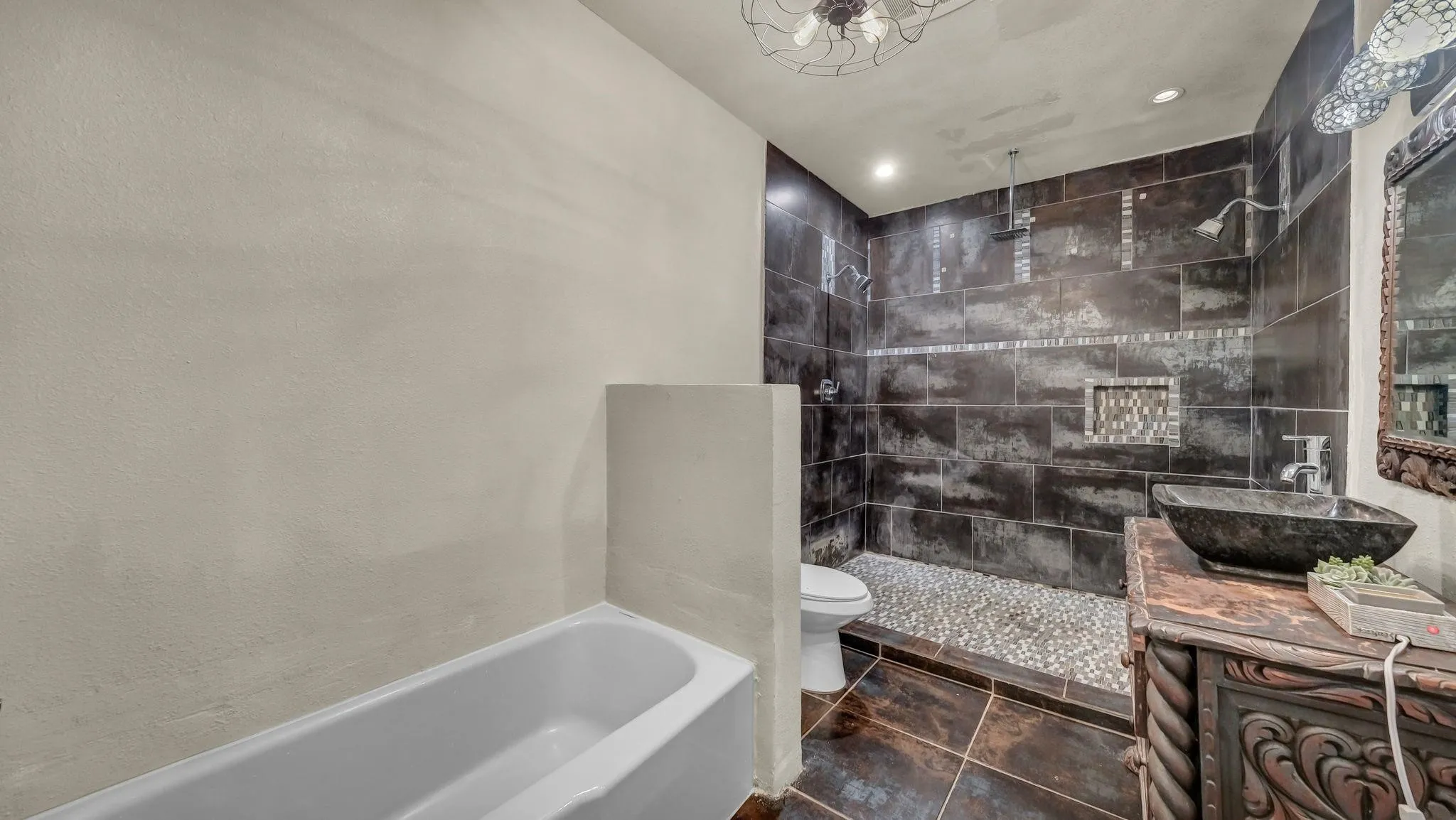 soaking tub, dark tiled walk-in shower with pebble floor, dual shower heads, and an integrated shelf
