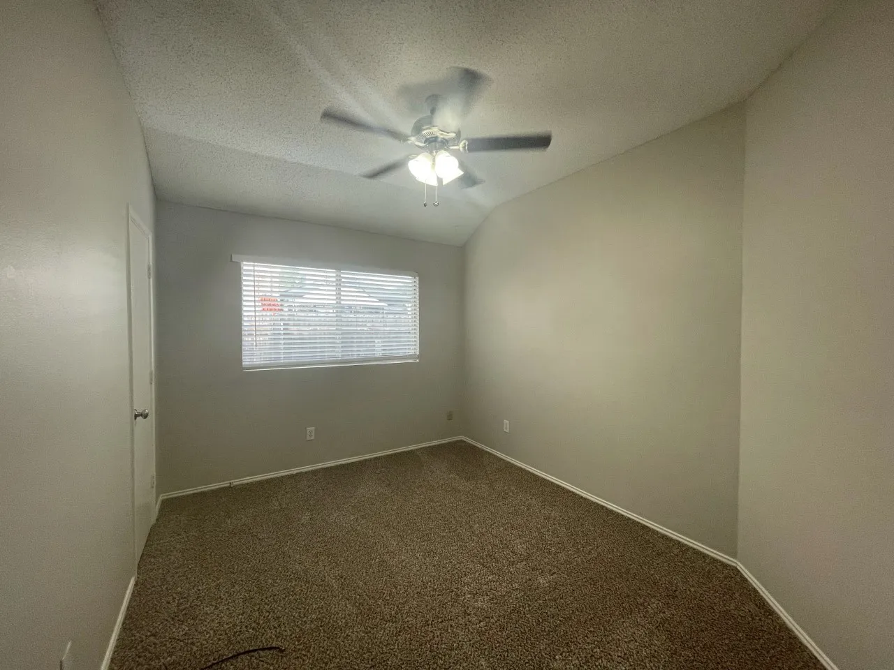 Sloped ceiling with a ceiling fan, window with blinds, light-colored walls, and carpet flooring