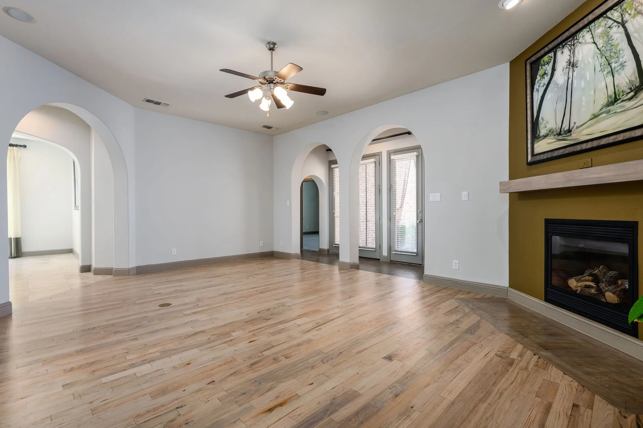 Arched entryways, wood-finish flooring, built-in fireplace, and recessed lighting