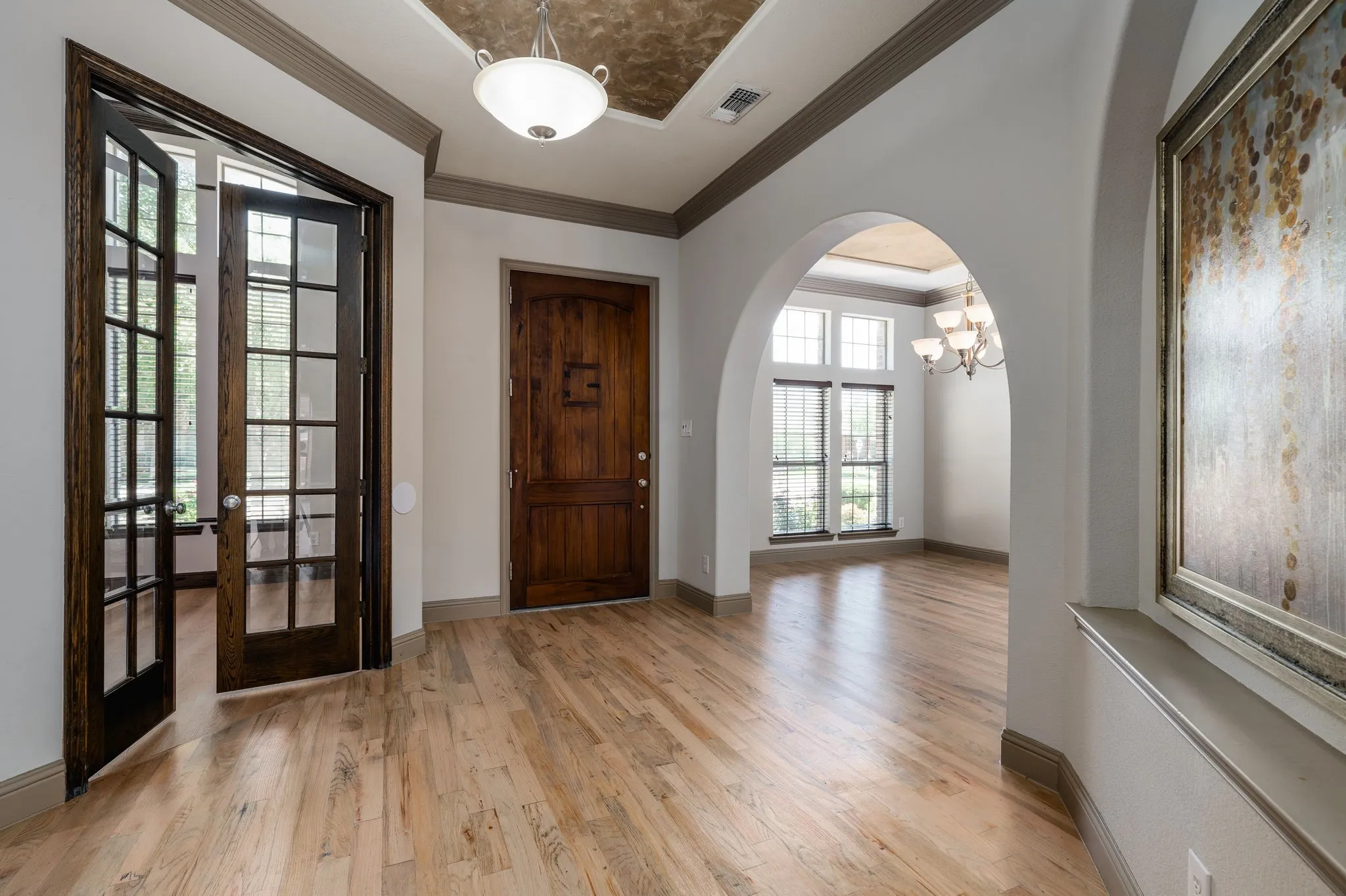 Hardwood flooring throughout, with a decorative wooden front door and French doors