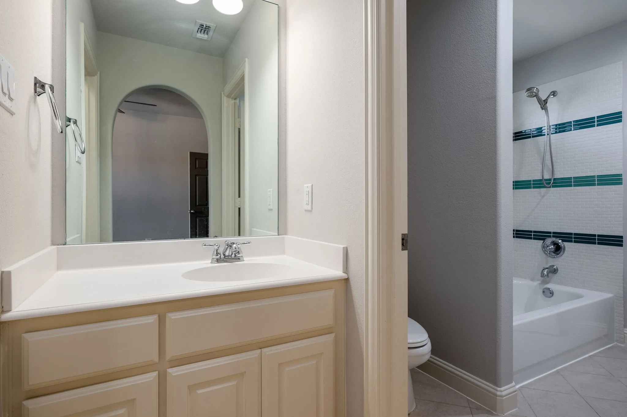 Single vanity with a white countertop and integrated sink, a large mirror, a chrome faucet, and under-sink cabinetry