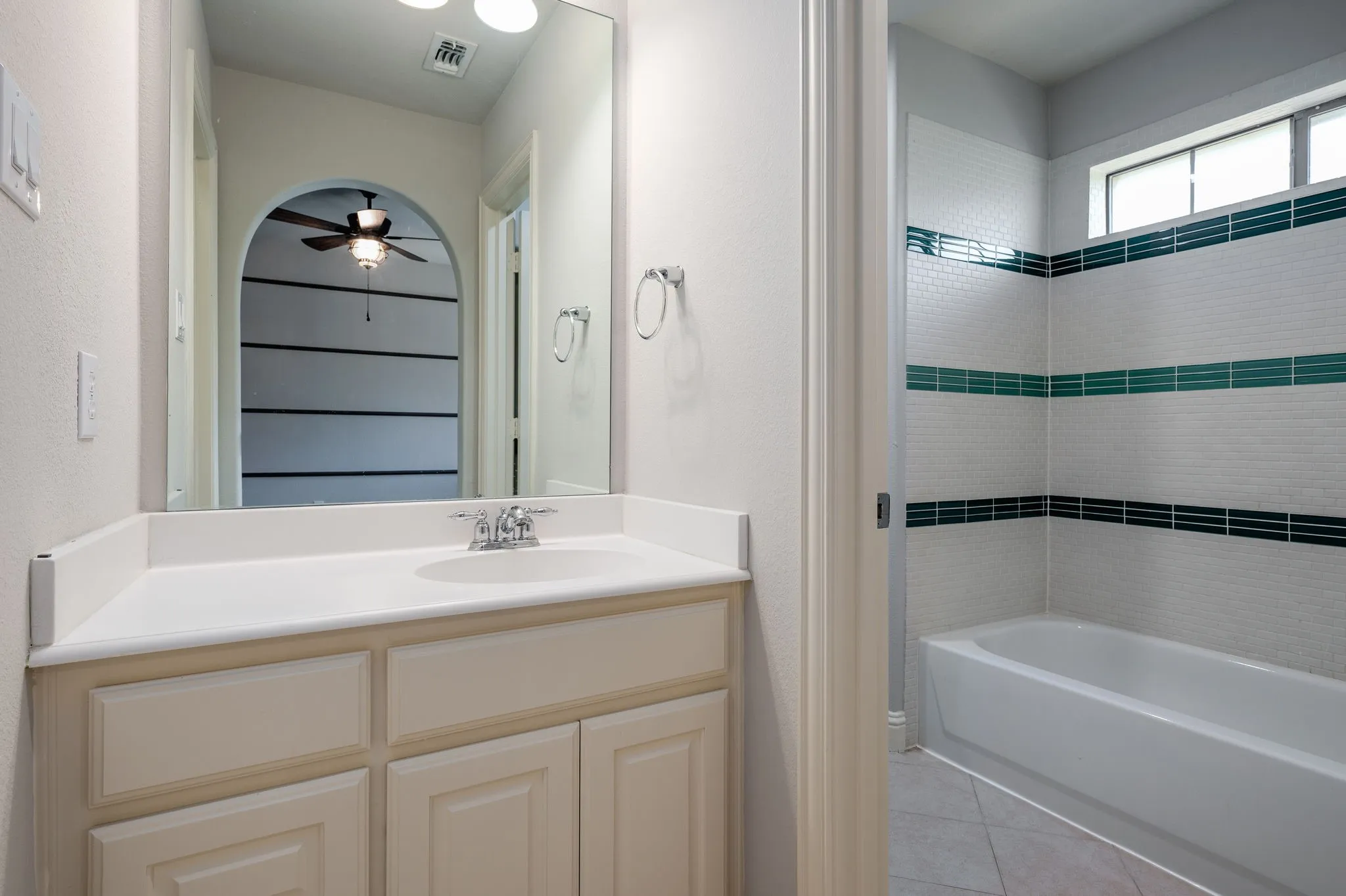 Bathroom featuring a single vanity with a white countertop, chrome faucet, and white cabinetry