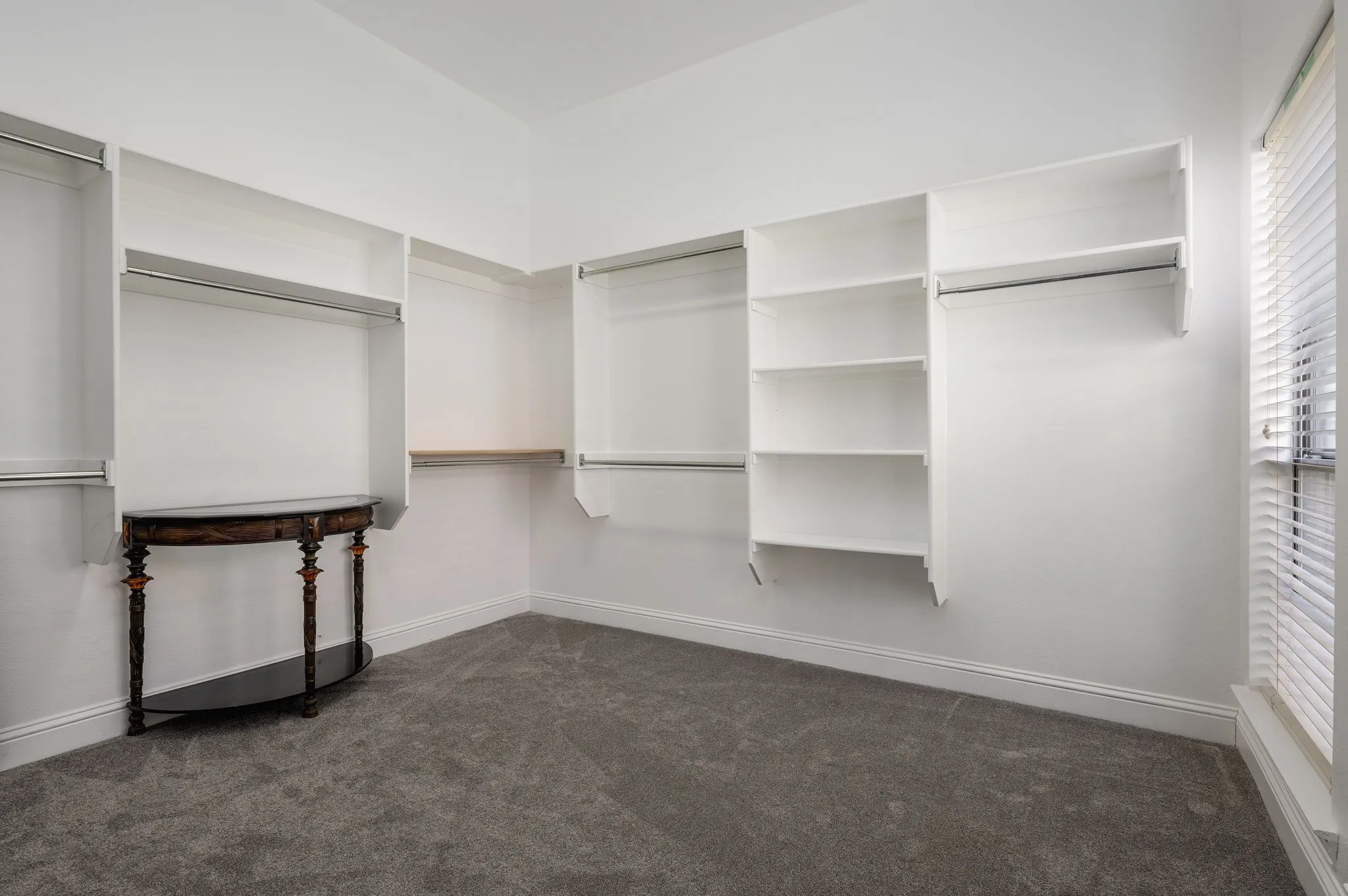 Built-in white shelving, integrated hanging rods, and light gray carpeting
