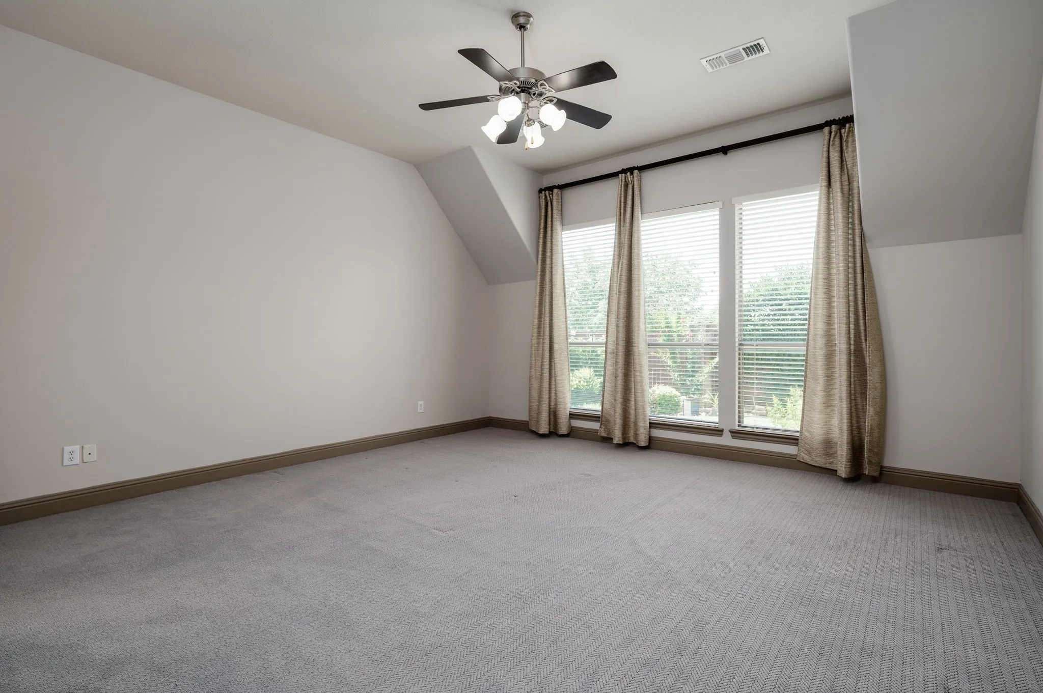 Wall-to-wall carpeting and a ceiling fan with light fixture