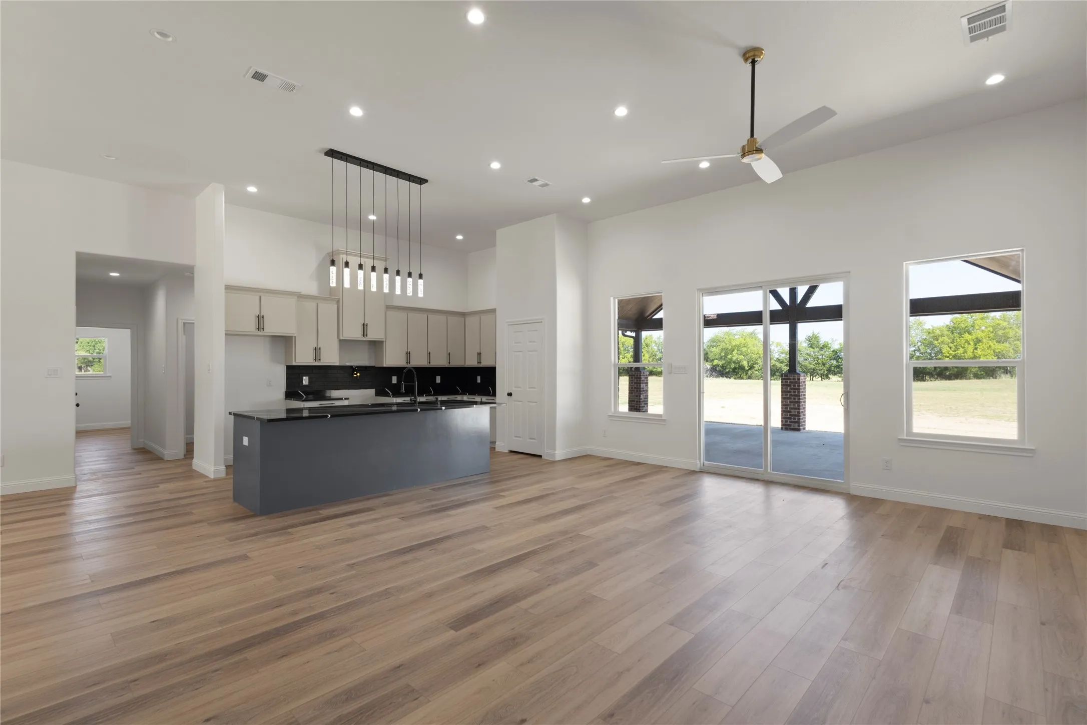 Kitchen featuring light-toned cabinetry, dark subway tile backsplash, dark countertops, and a built-in sink with a gooseneck faucet