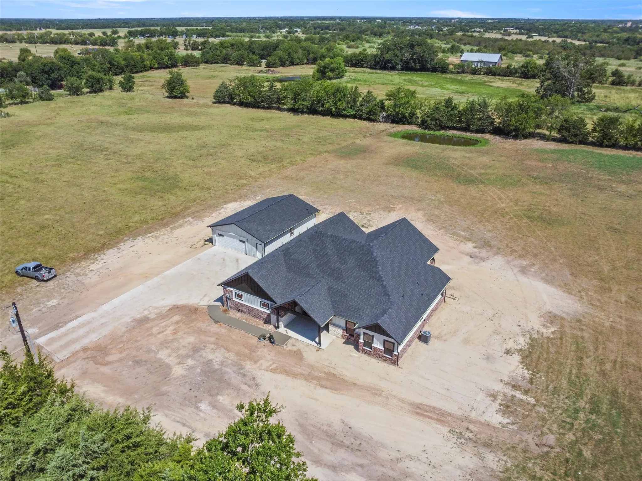 Single-story residence with a dark shingle roof, brick and siding exterior, an attached covered porch, and an additional detached structure with a garage door