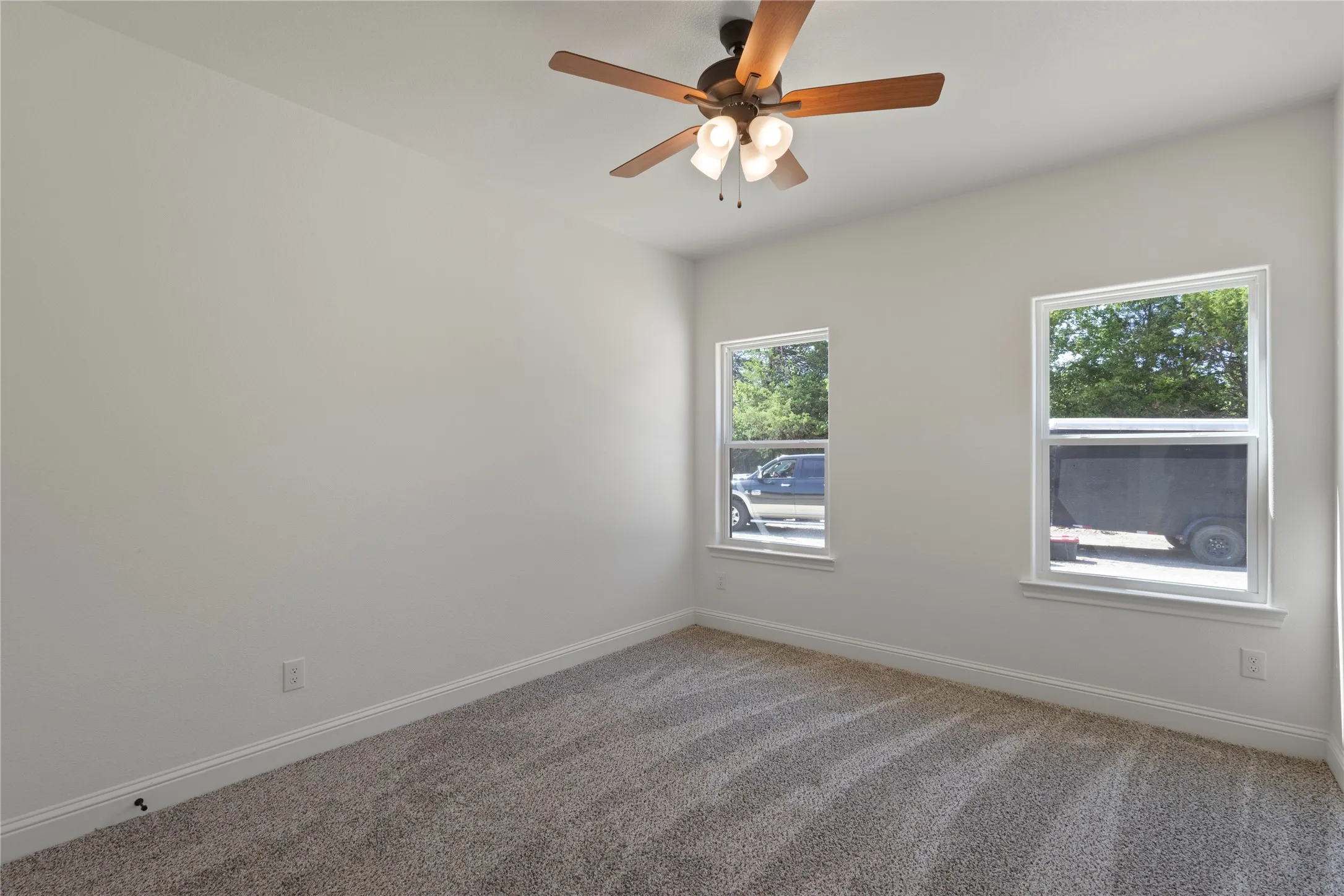 Neutral wall paint with carpet flooring, a ceiling fan with integrated lighting, and a single window with white trim