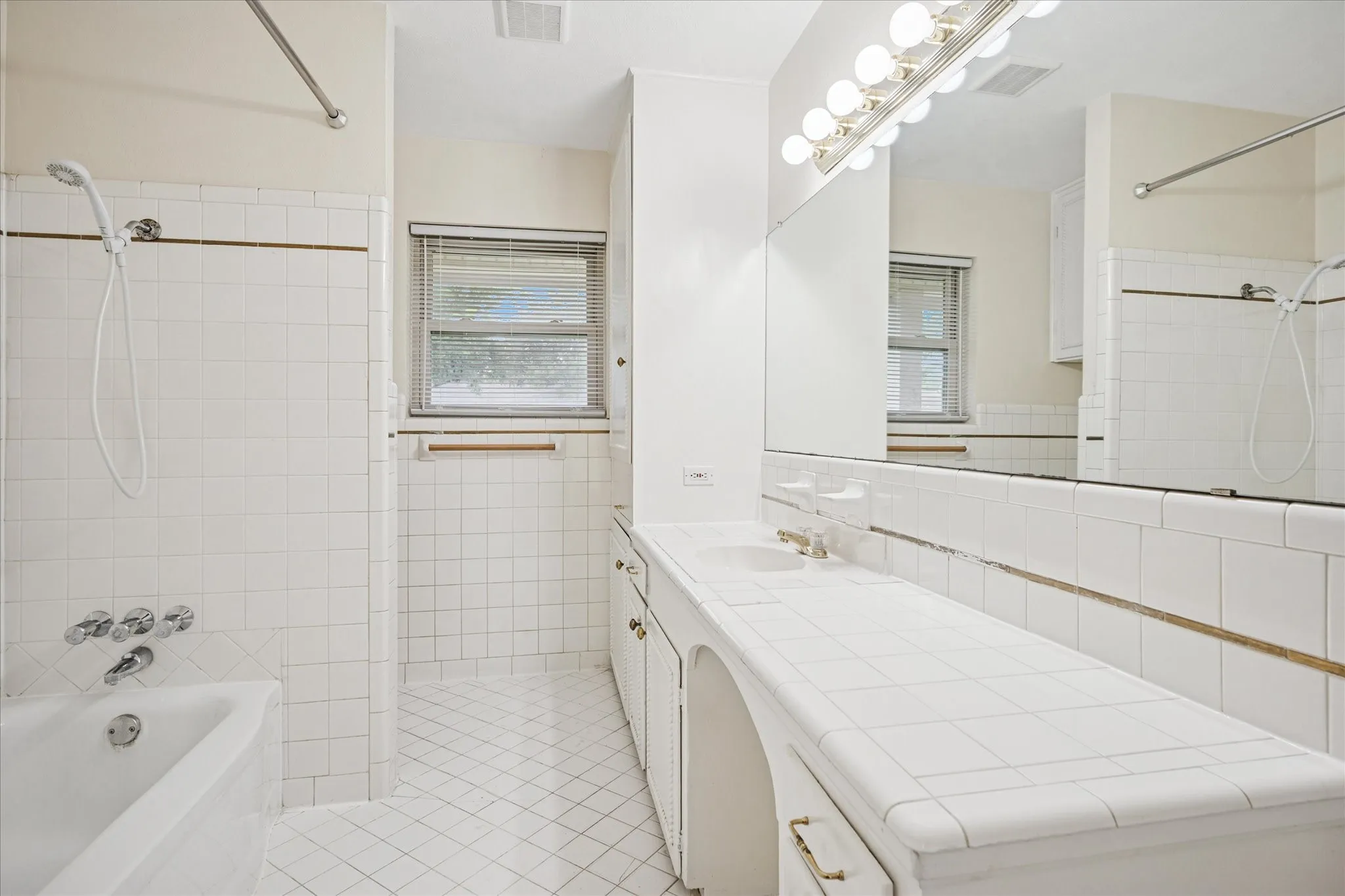 Hall bath with tub and showerhead. Opens to bedroom three.