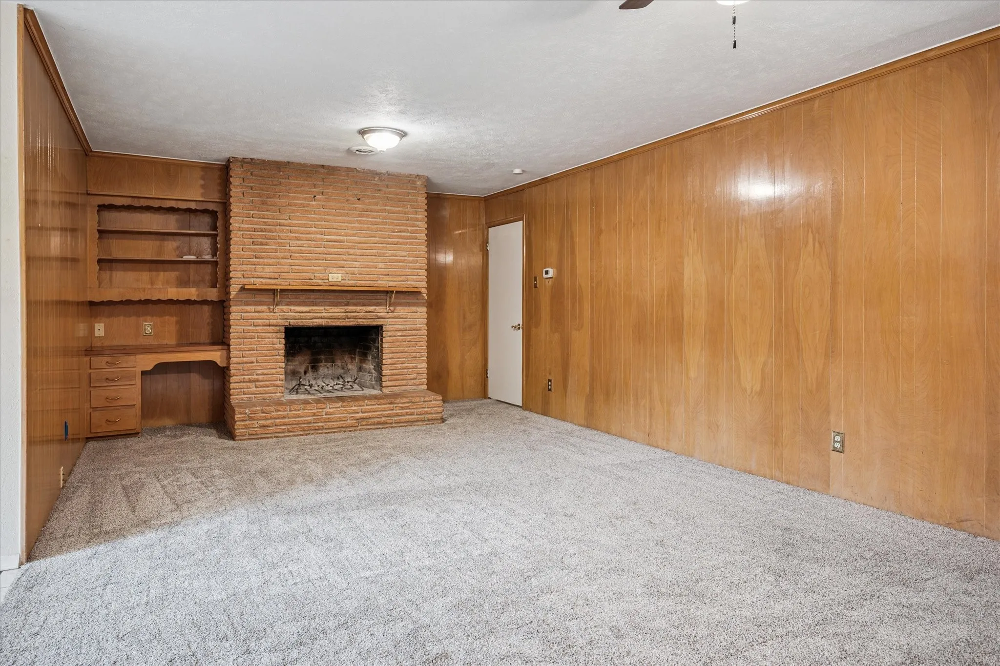 Be cozy all winter with two fireplaces! Here's the second WBFP with gas starter. Natural wood-paneled den with built-in desk and shelves opens to covered patio.