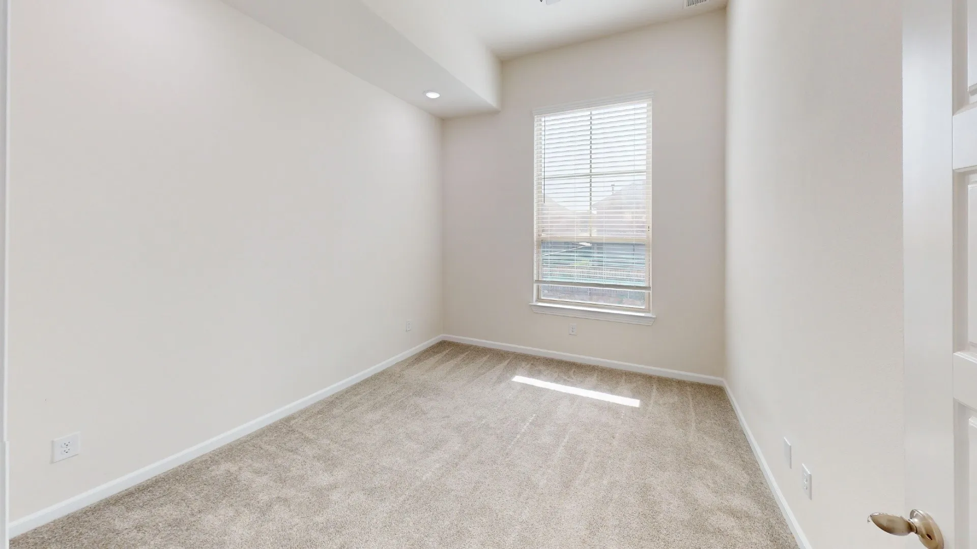Recessed ceiling lighting, light-toned wall paint, carpeted flooring, window with blinds, and white interior door