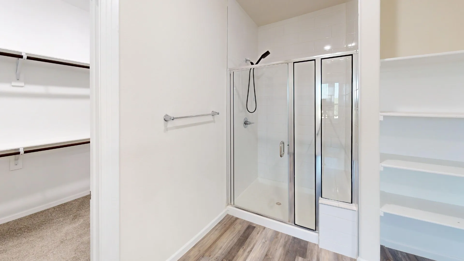Glass-enclosed shower with subway tile surround, wood-finish flooring, and built-in shelving