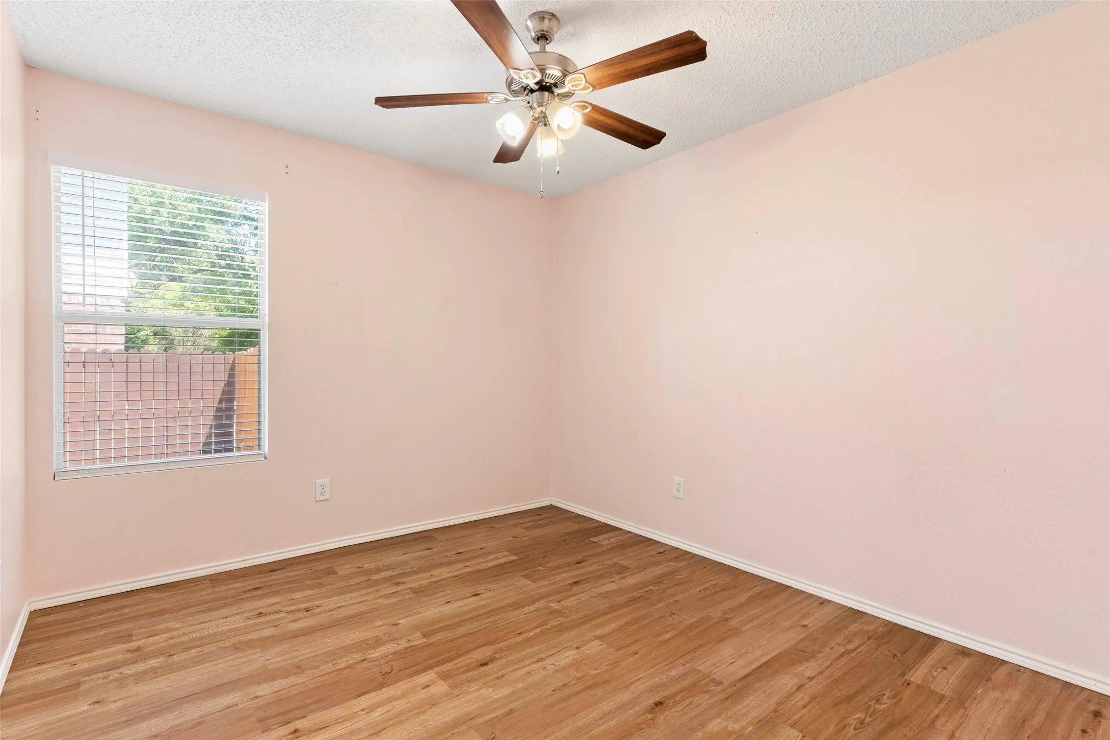 Wood-finish flooring, ceiling fan with light fixture, and a window with blinds