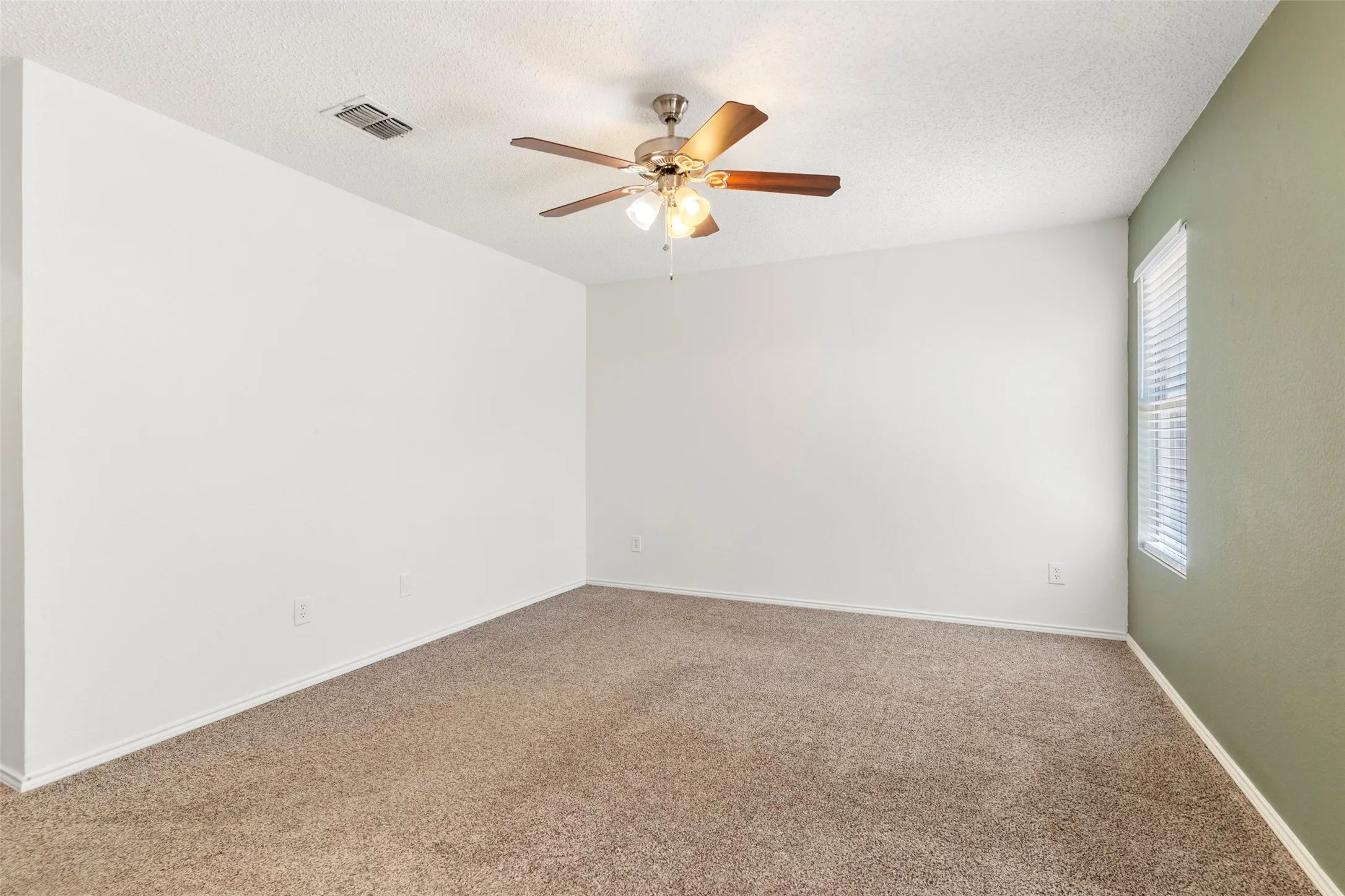 Wall-to-wall carpeting with a ceiling fan light fixture and a window with blinds