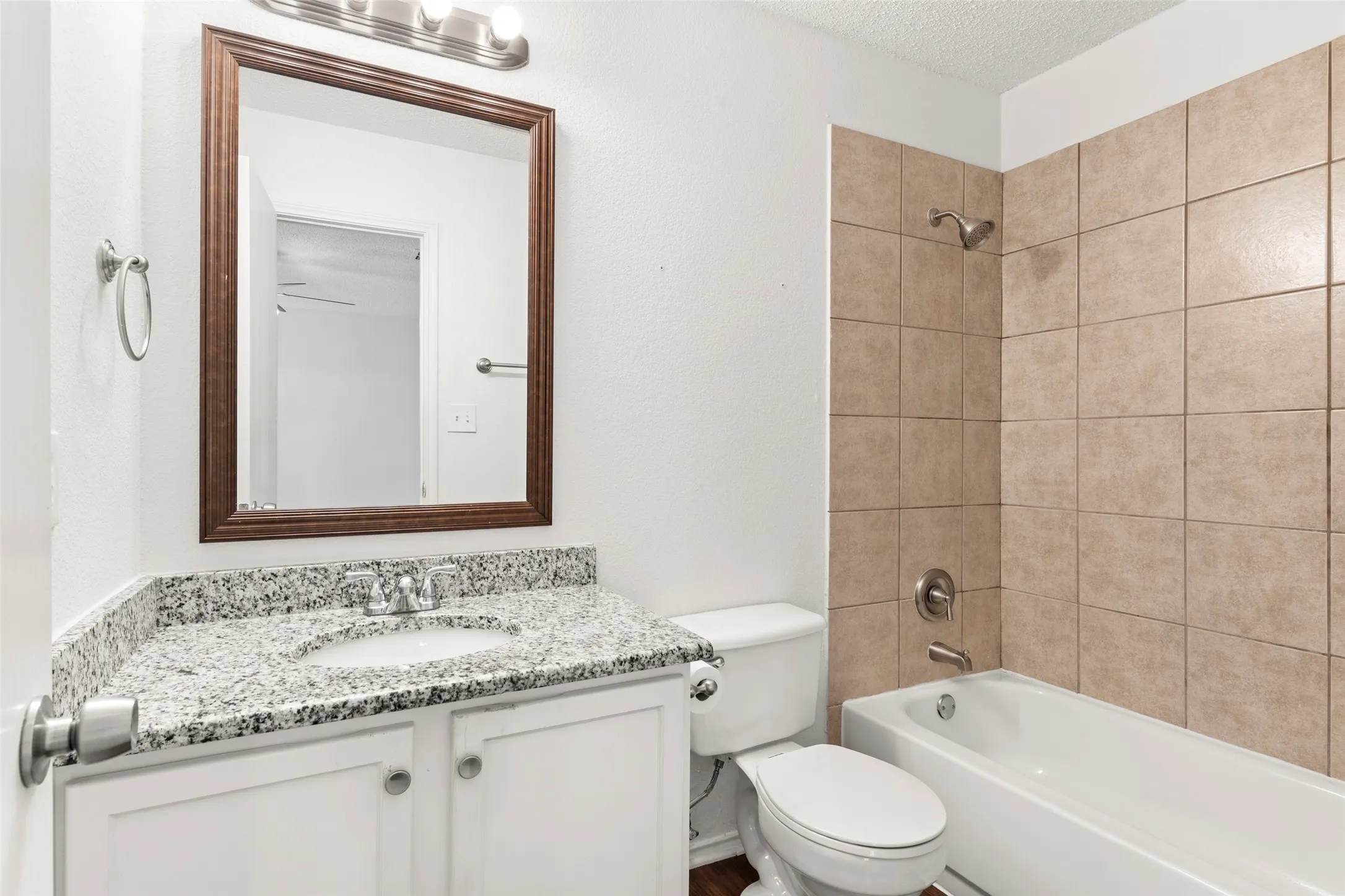 Bathroom featuring a vanity with a granite-style countertop, undermount sink, and white cabinetry