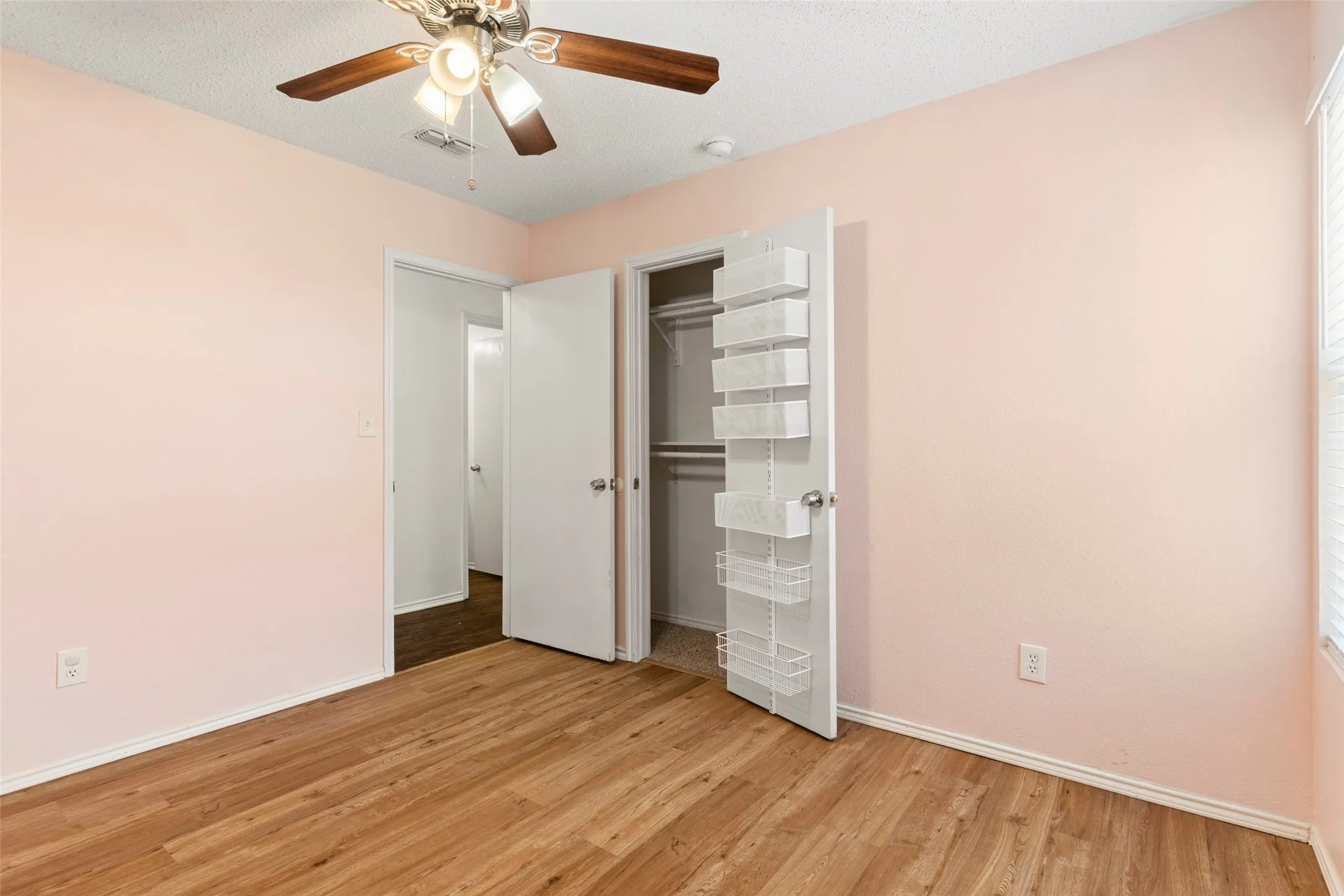 Wood-finish flooring, ceiling fan with light fixture, and a built-in closet with shelving