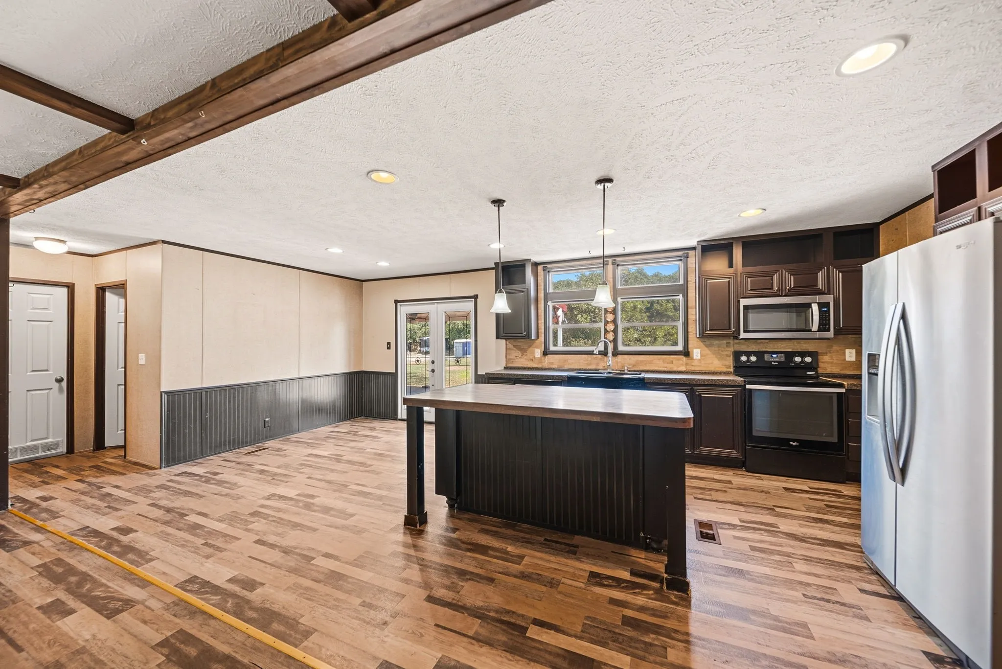 Open-concept kitchen and living area featuring wood-finish flooring, recessed lighting, and a kitchen island with pendant lighting
