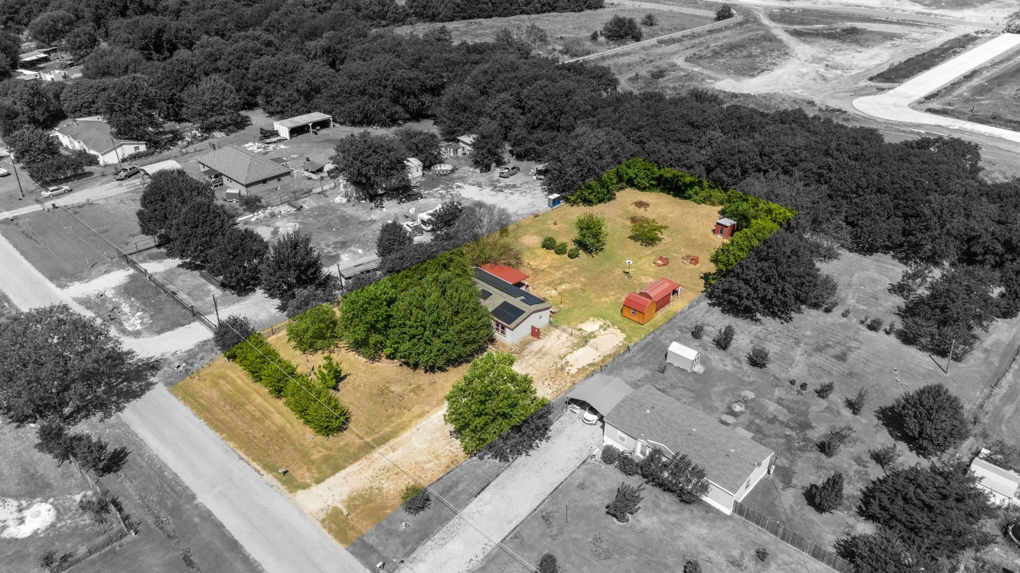 Spacious lot with mature trees, two red outbuildings, and ample open ground