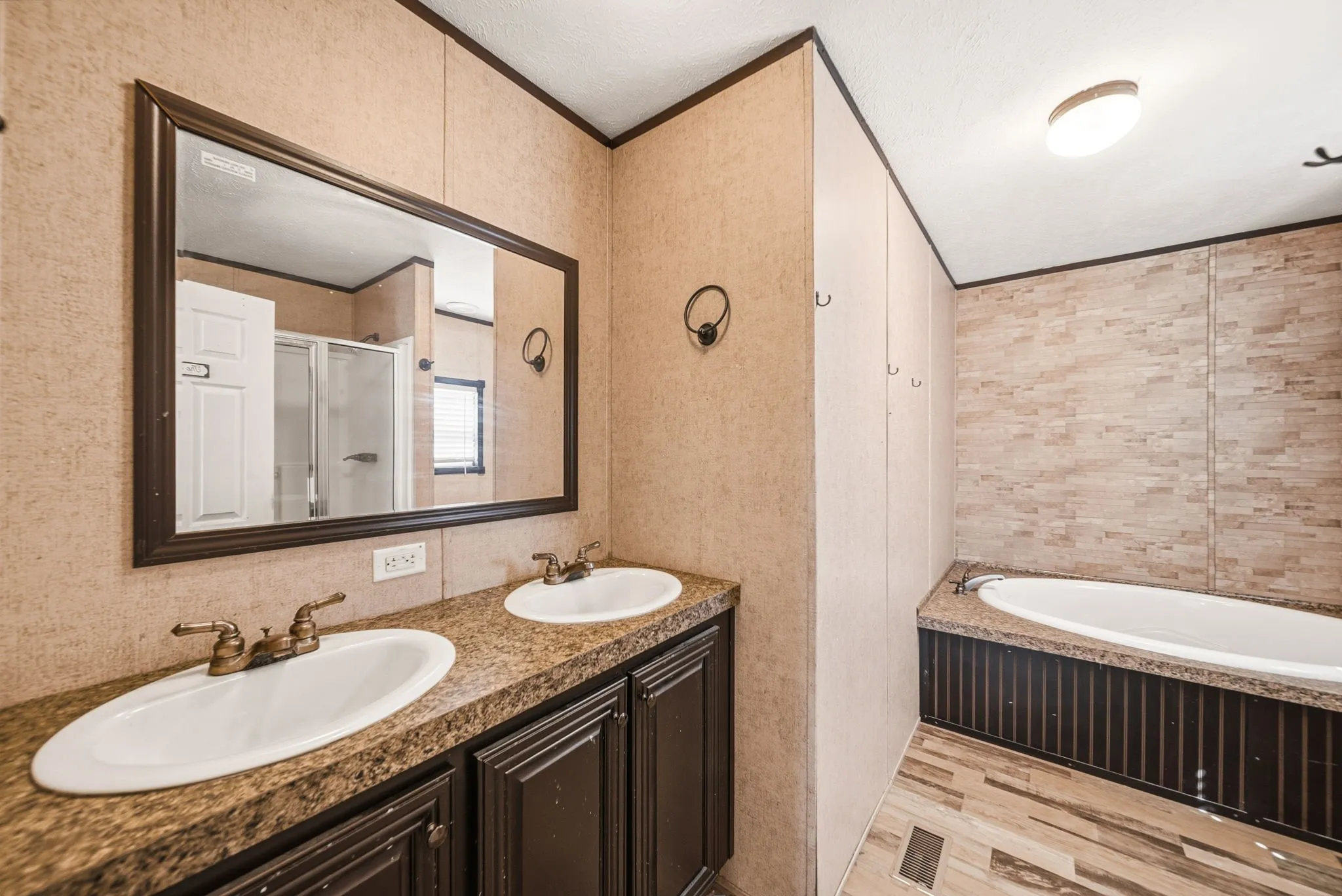 Dual vanity with undermount sinks, bronze-finish faucets, and a framed mirror