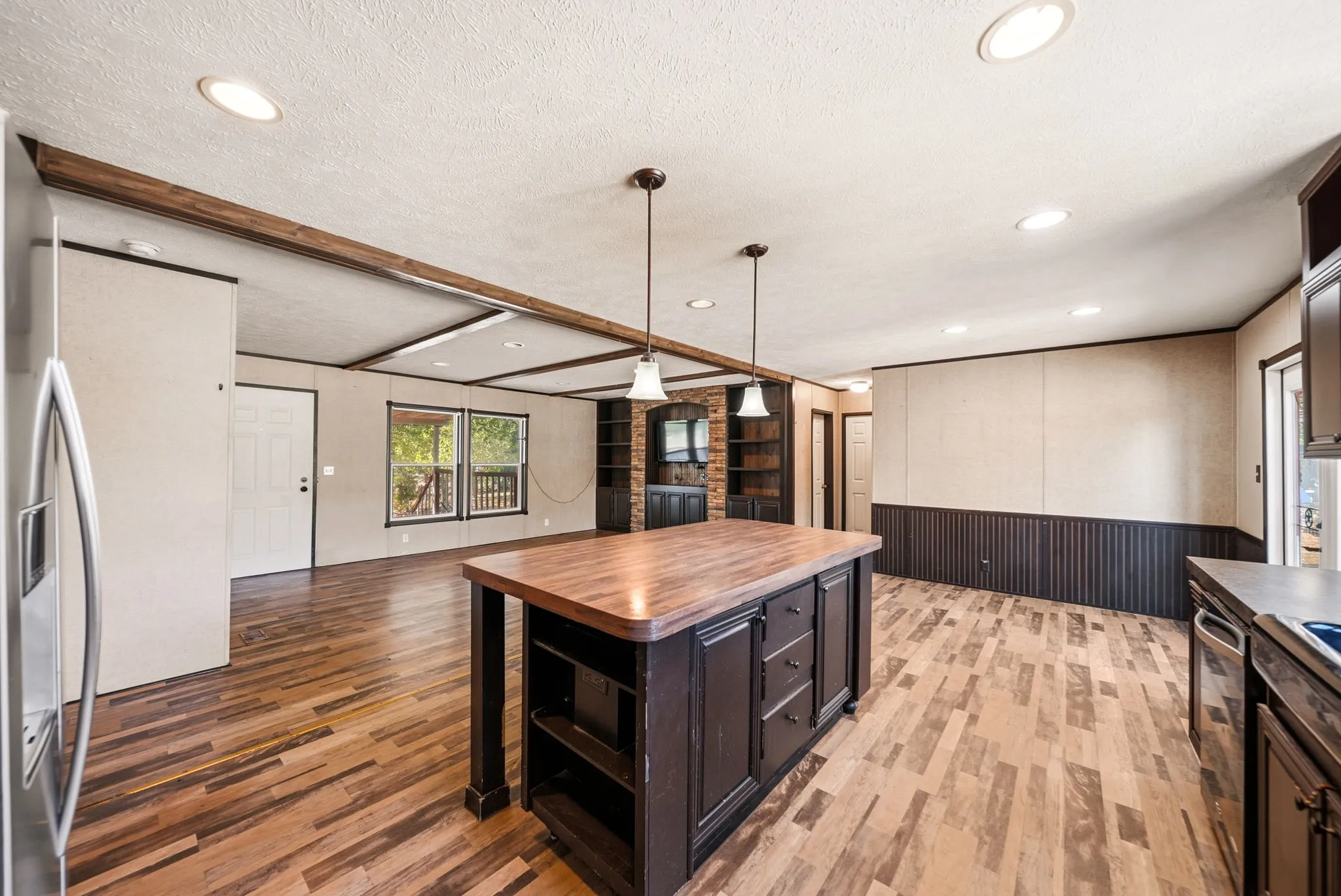 Spacious room with wood-finish flooring, recessed lighting, and exposed ceiling beams
