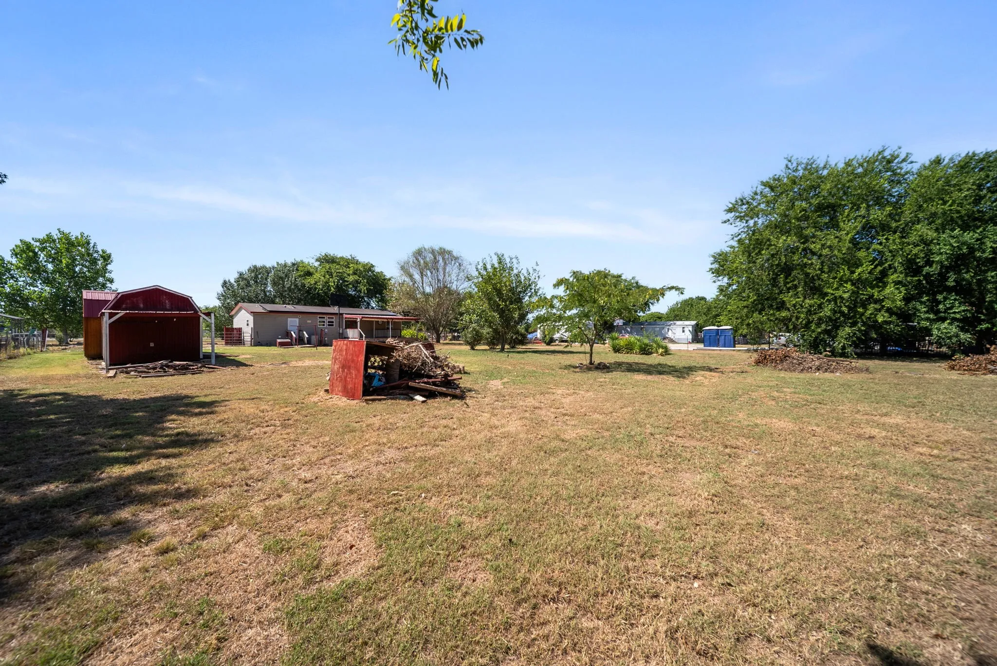 Expansive property with a residential structure, mature trees, and a red barn structure