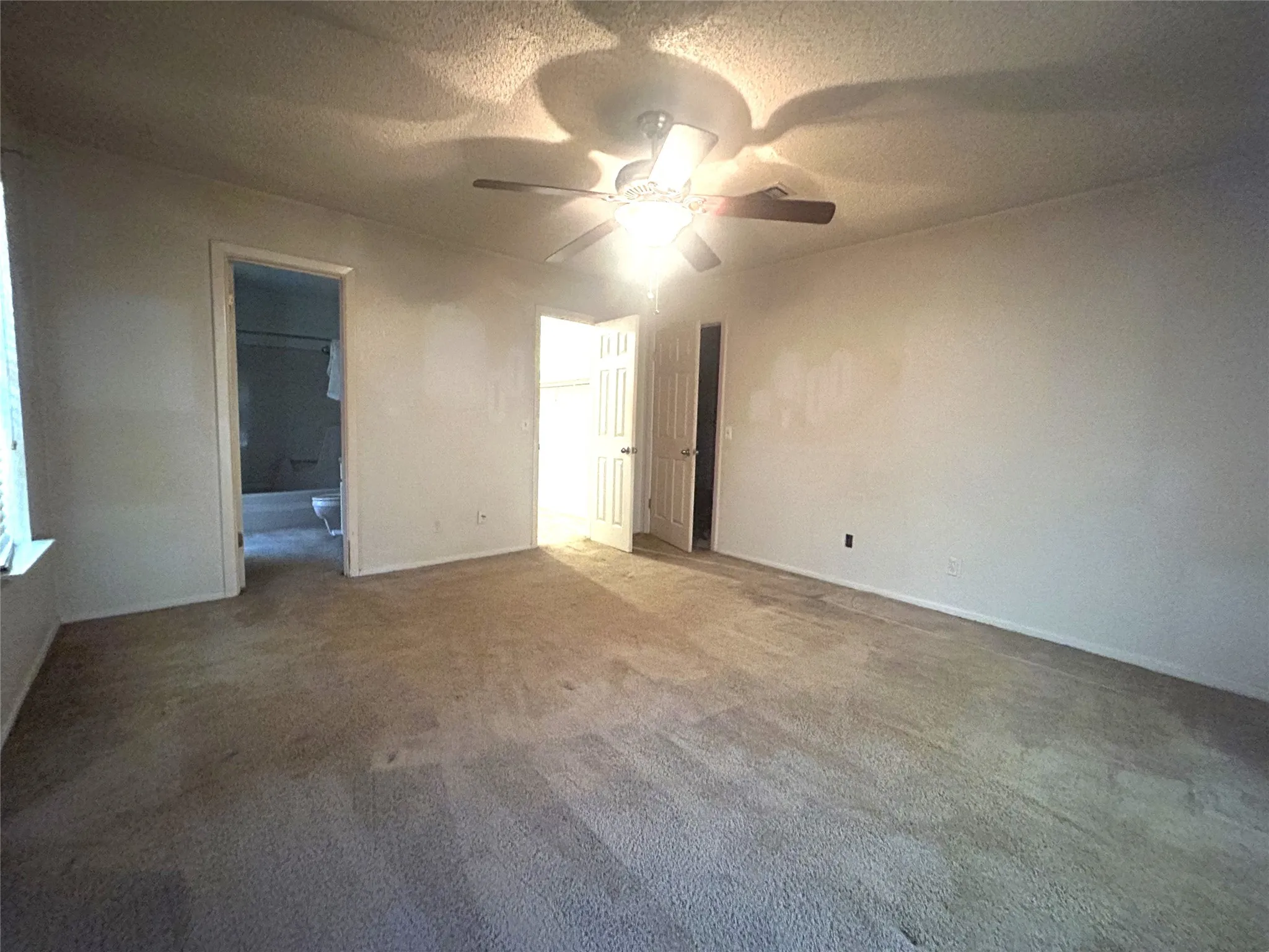 Primary bedroom looking toward the entry door to the right, walk in closet and private bathroom