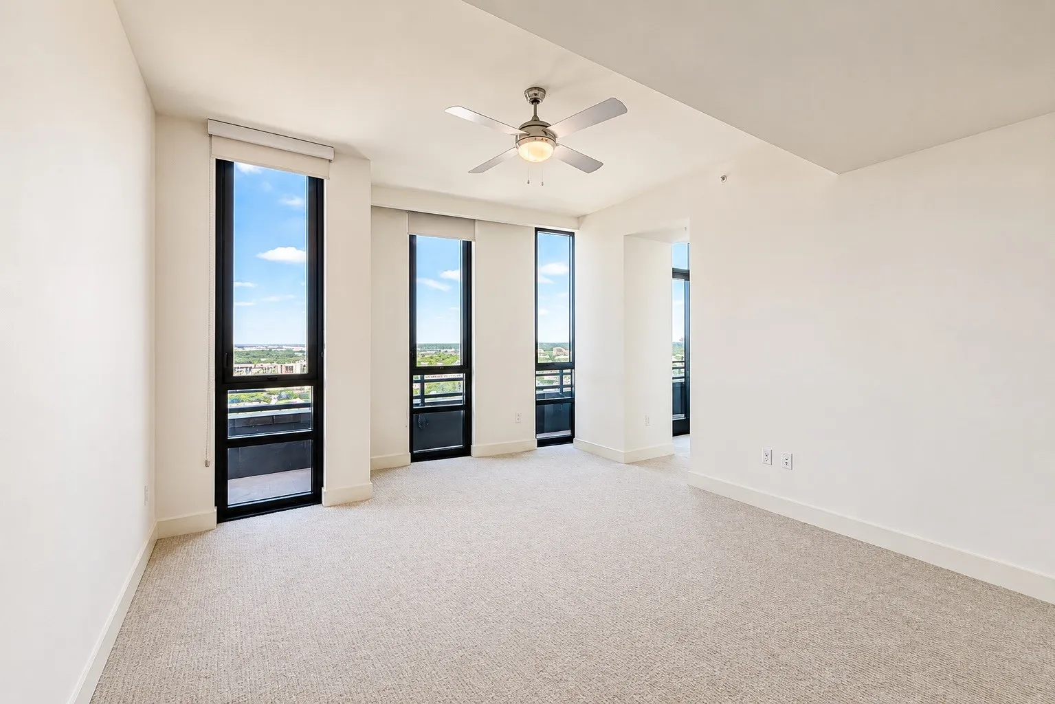 Floor-to-ceiling windows, roller shades, light-colored carpeting, recessed lighting, and a ceiling fan with integrated light