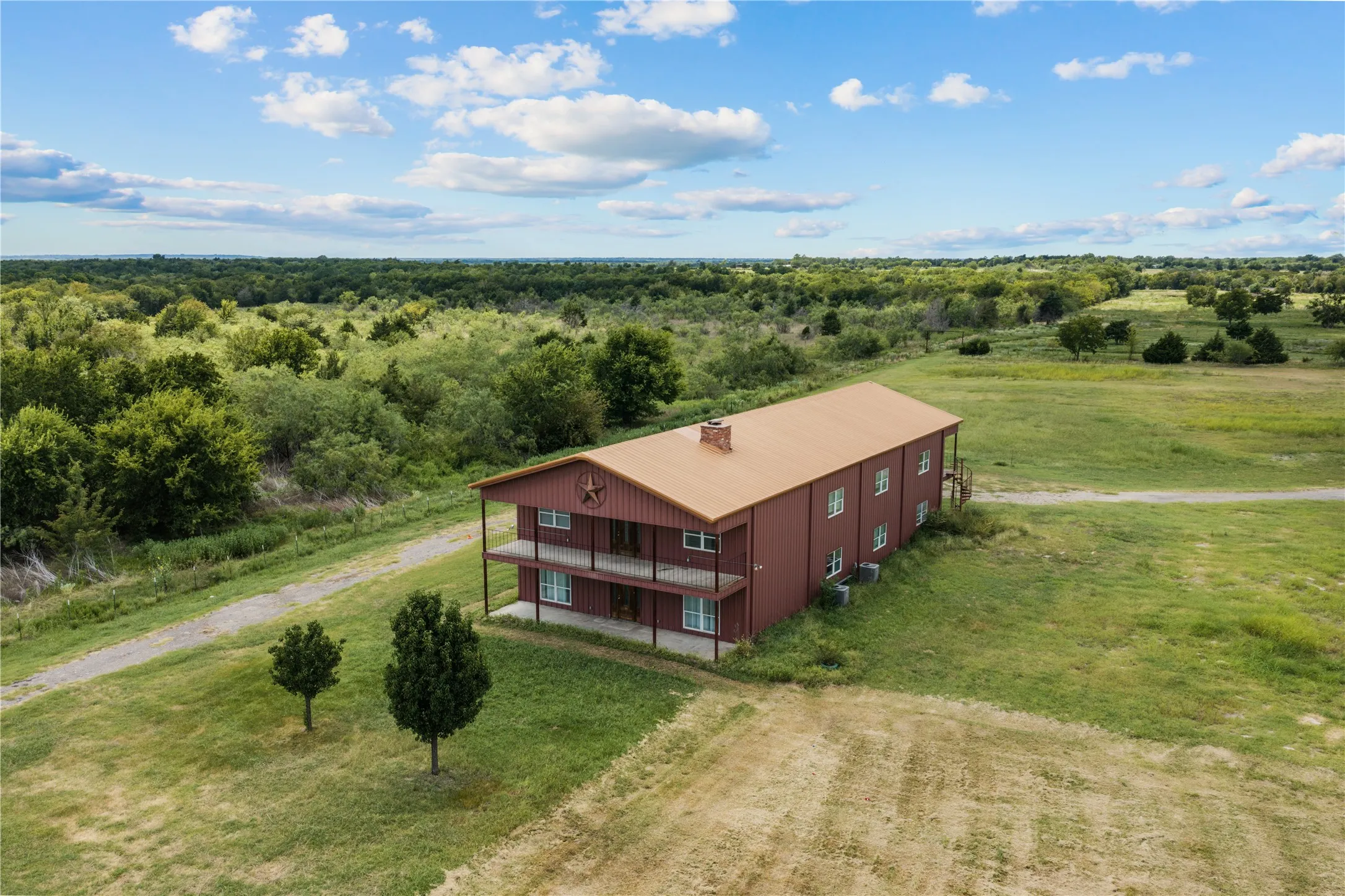Barn-style residence featuring a metal roof, two-story covered balconies, and a red exterior