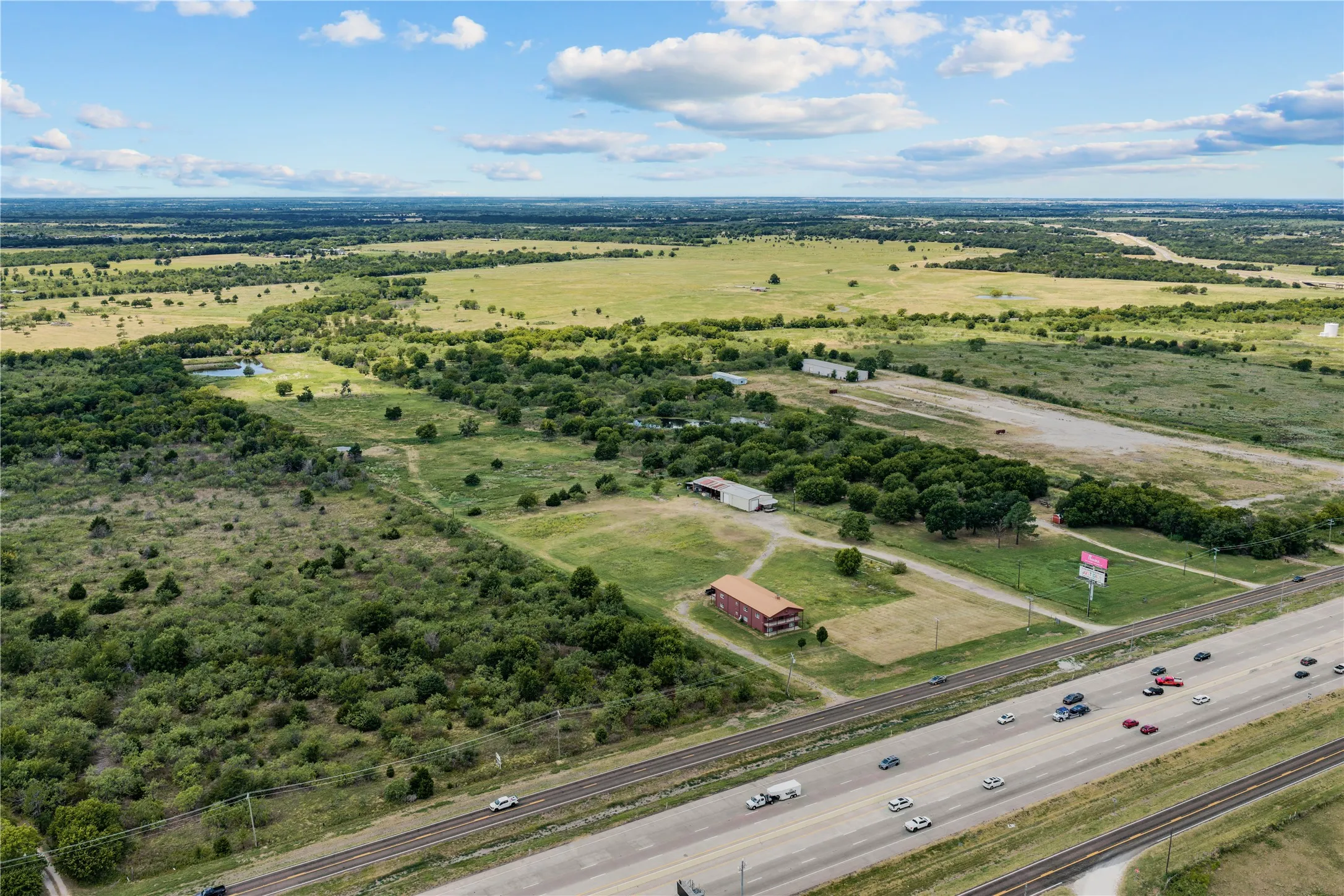 Expansive acreage with diverse terrain featuring open pastures, wooded areas, and a visible pond