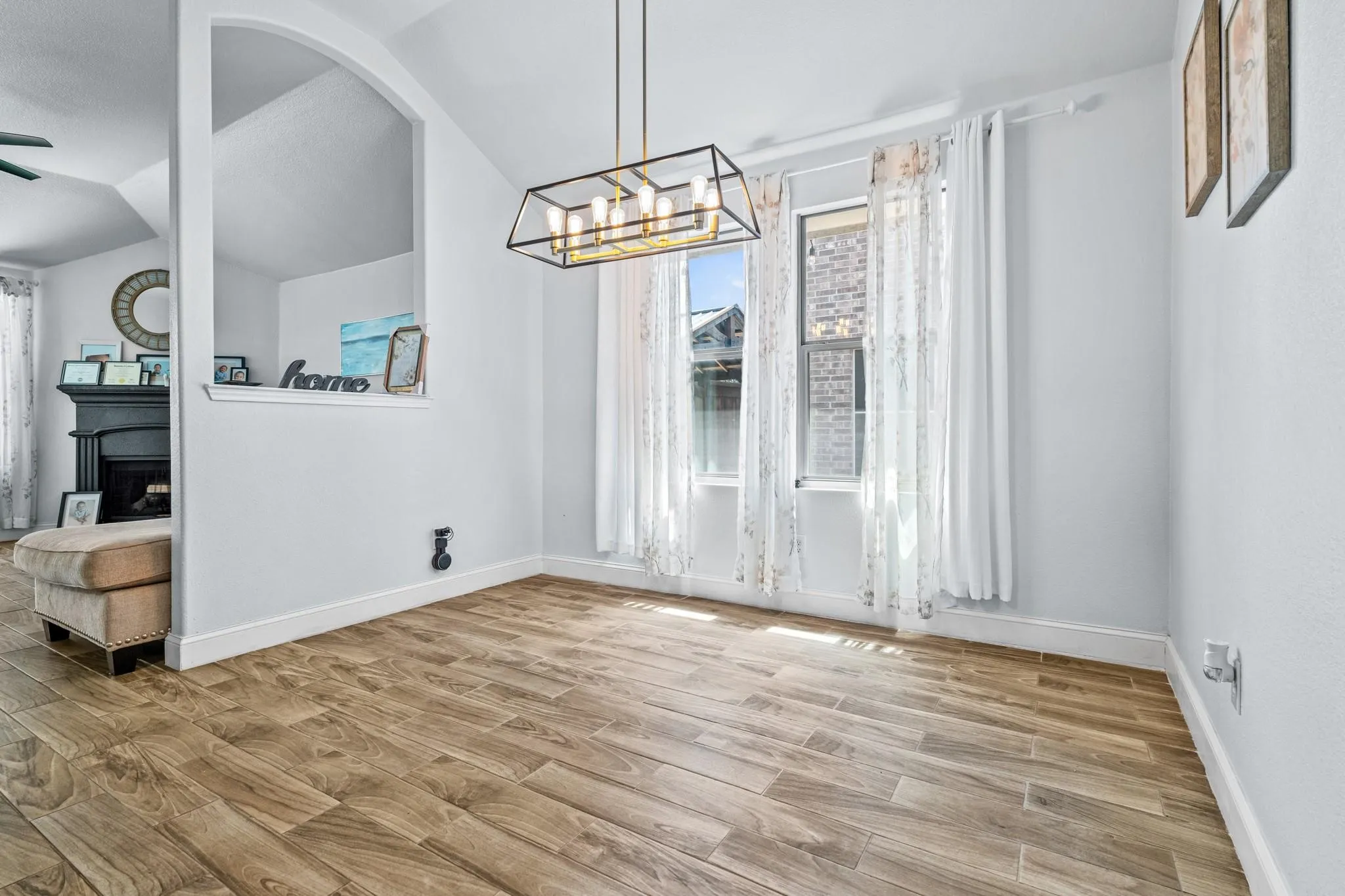 Vaulted ceiling with a geometric chandelier, wood-finish flooring, and arched architectural detail