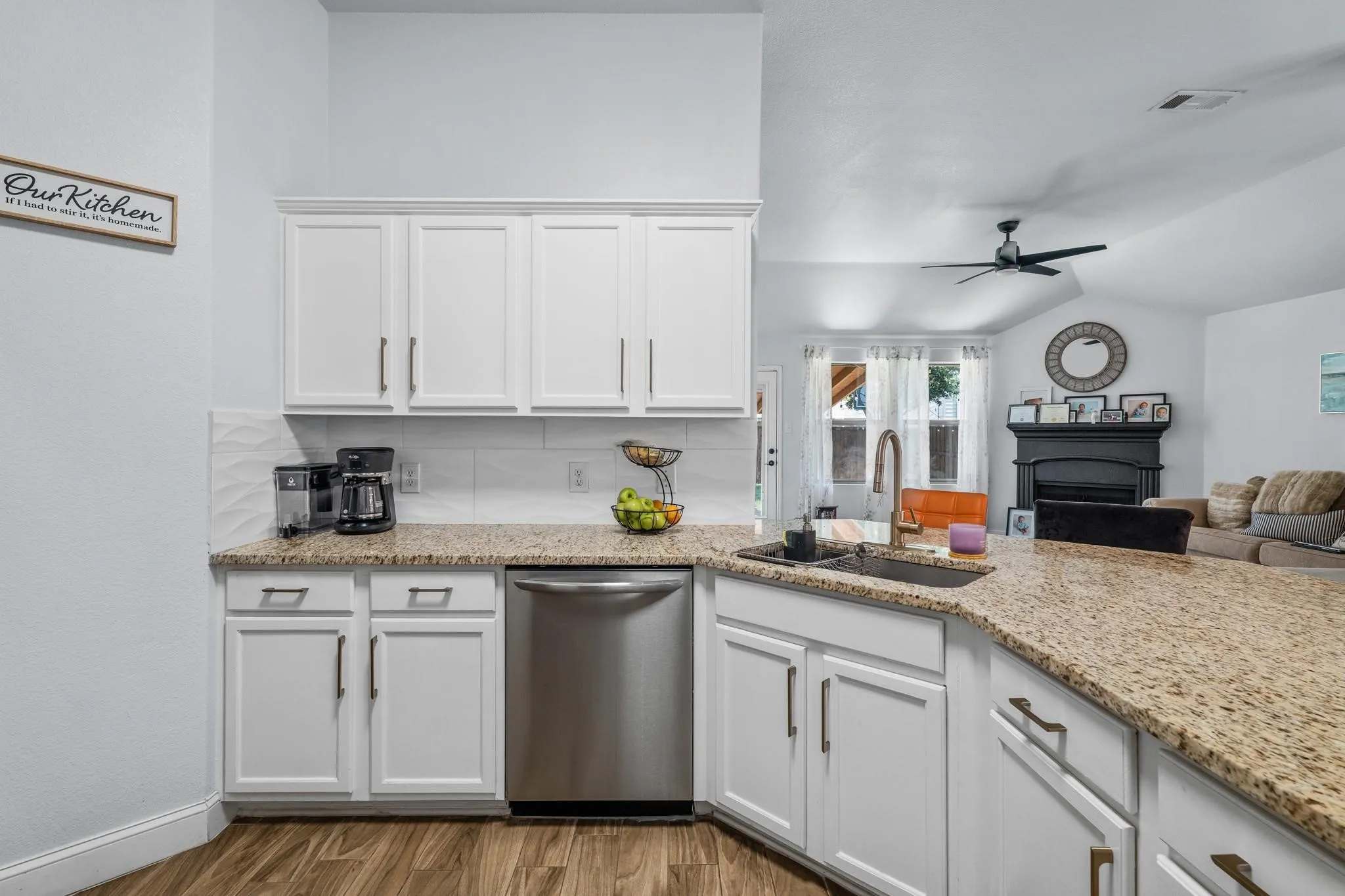 White cabinetry with linear hardware, light-toned countertop, stainless steel dishwasher, wood-finish flooring, and recessed lighting