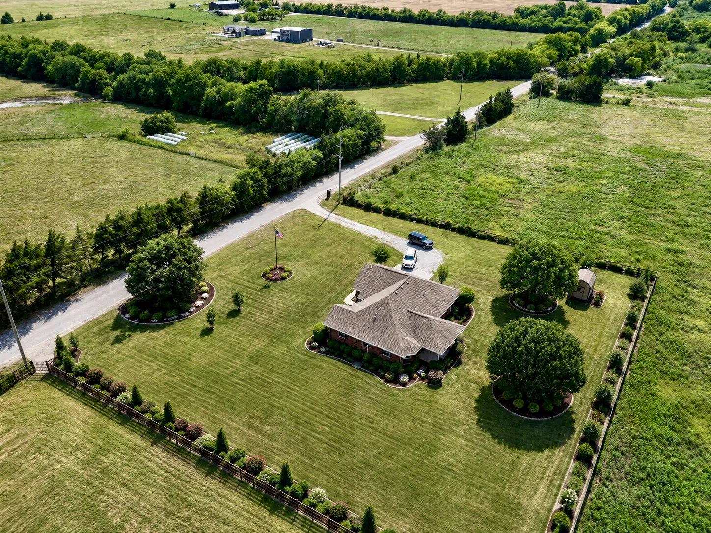 Expansive property featuring a single-story residence with a multi-gabled roof, a gravel driveway, and a large manicured lawn