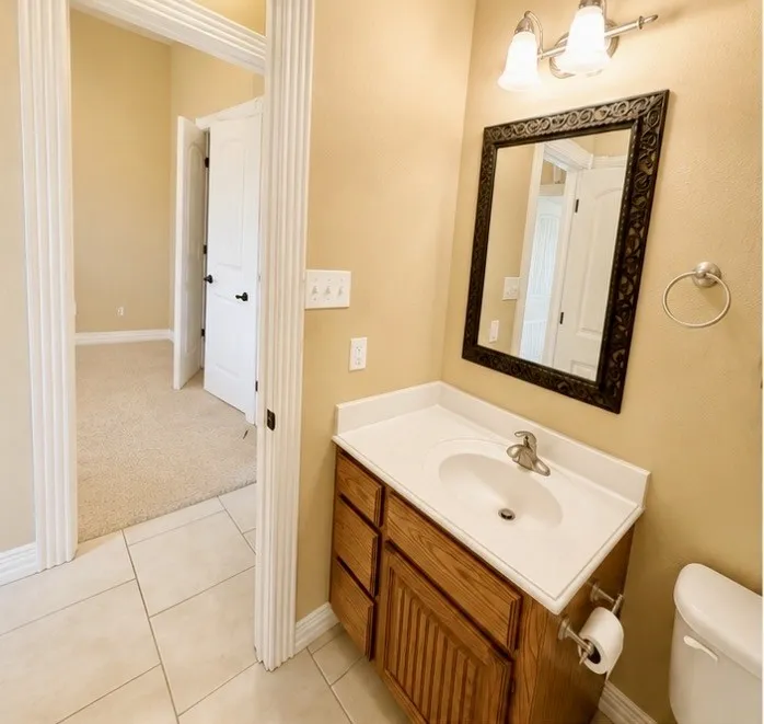 Bathroom featuring a wood-finish vanity with a white countertop, an undermount sink, and tiled flooring