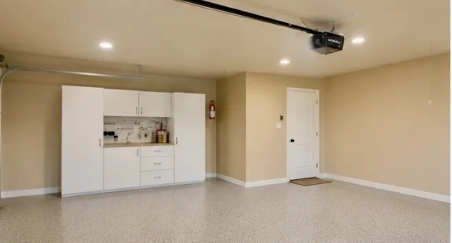 Epoxy-coated flooring, built-in white cabinetry, integrated workbench, overhead garage door opener, and recessed lighting