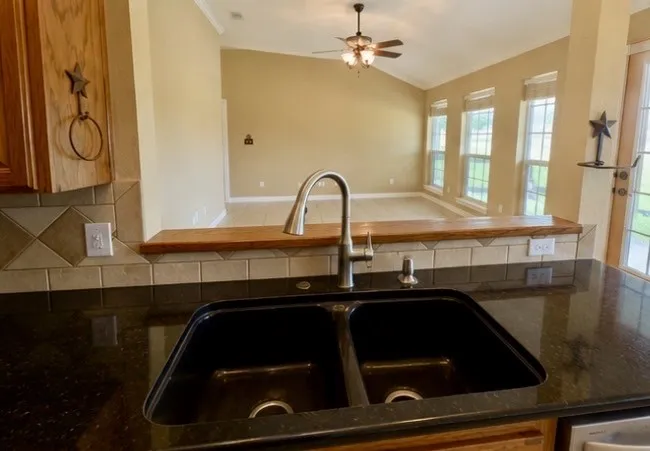 Kitchen sink with black granite countertop and gooseneck faucet