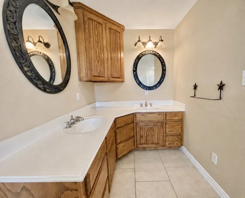 Dual vanity with undermount sinks, wood cabinetry, white countertops, and tile flooring