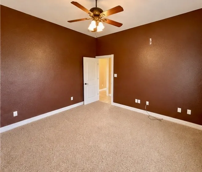 Spacious room with plush carpeting and a ceiling fan with integrated lighting